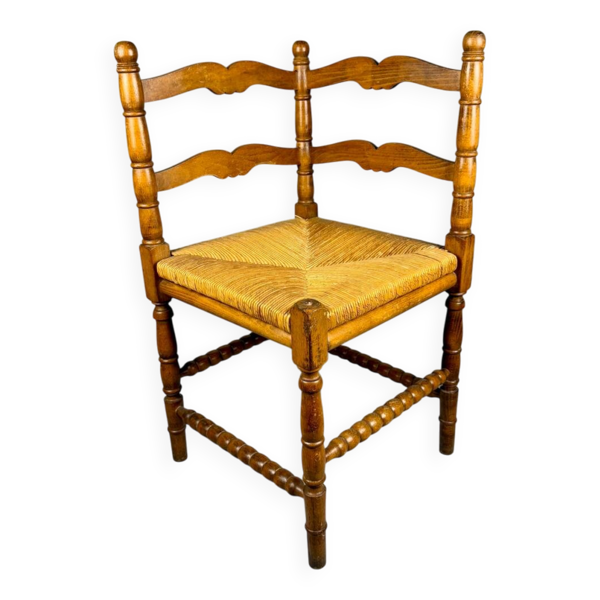 Chaise d'angle vintage en bois avec assise en paille tissée.