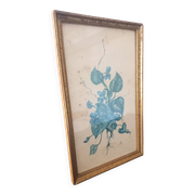 Decorative table with vintage blue flowers in a golden frame.