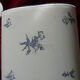 Old wall fountain in enamelled sheet metal decorated with blue flowers on a white background