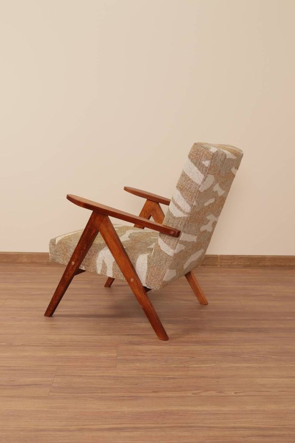 Fauteuil lounge vintage en tissu jacquard à motifs rétro et bois marron.