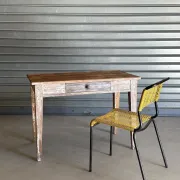 Vintage table made of raw wood with a distressed white base.