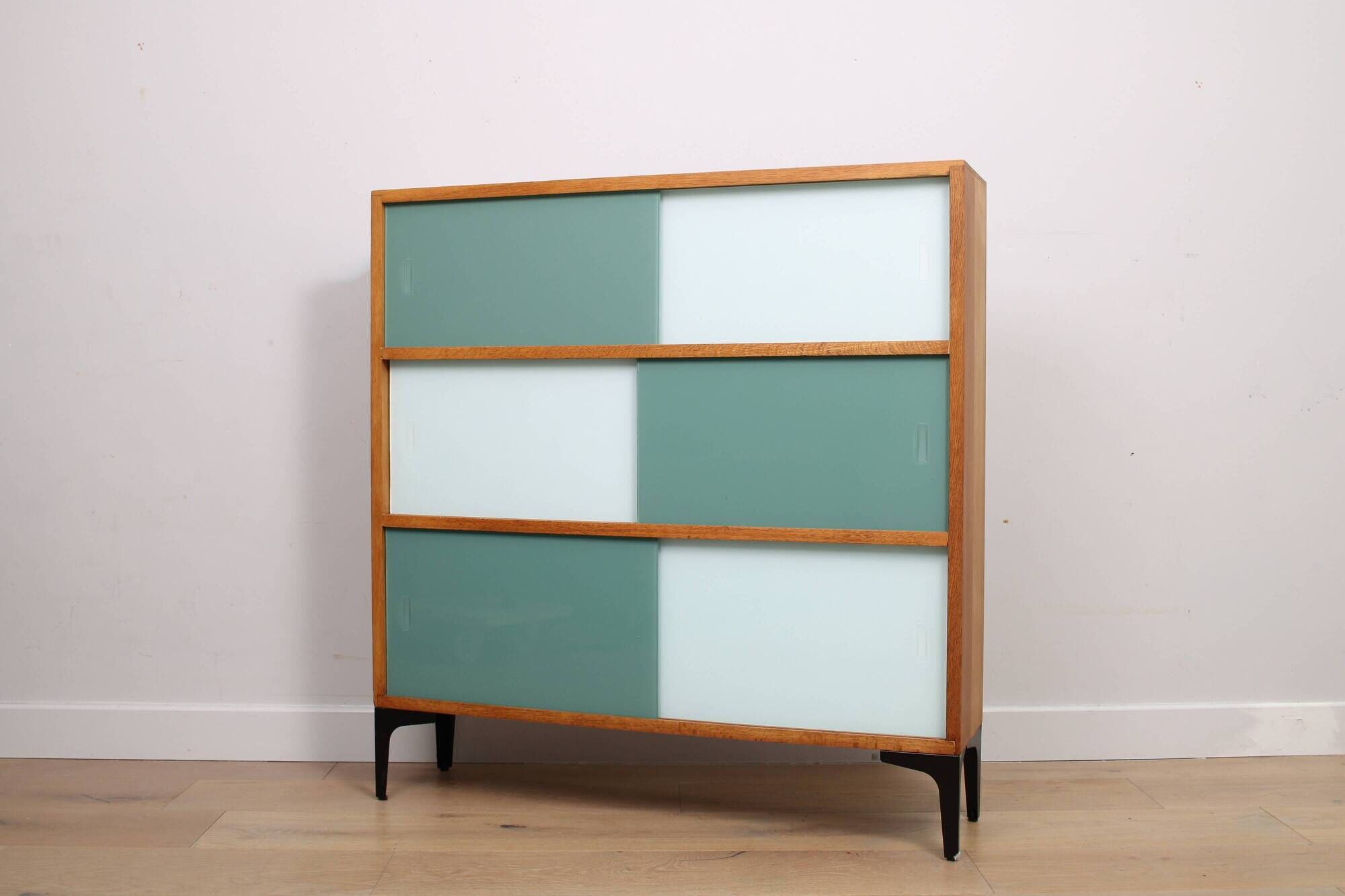 A vintage mid-century 3 tiered bookcase with glass sliding doors