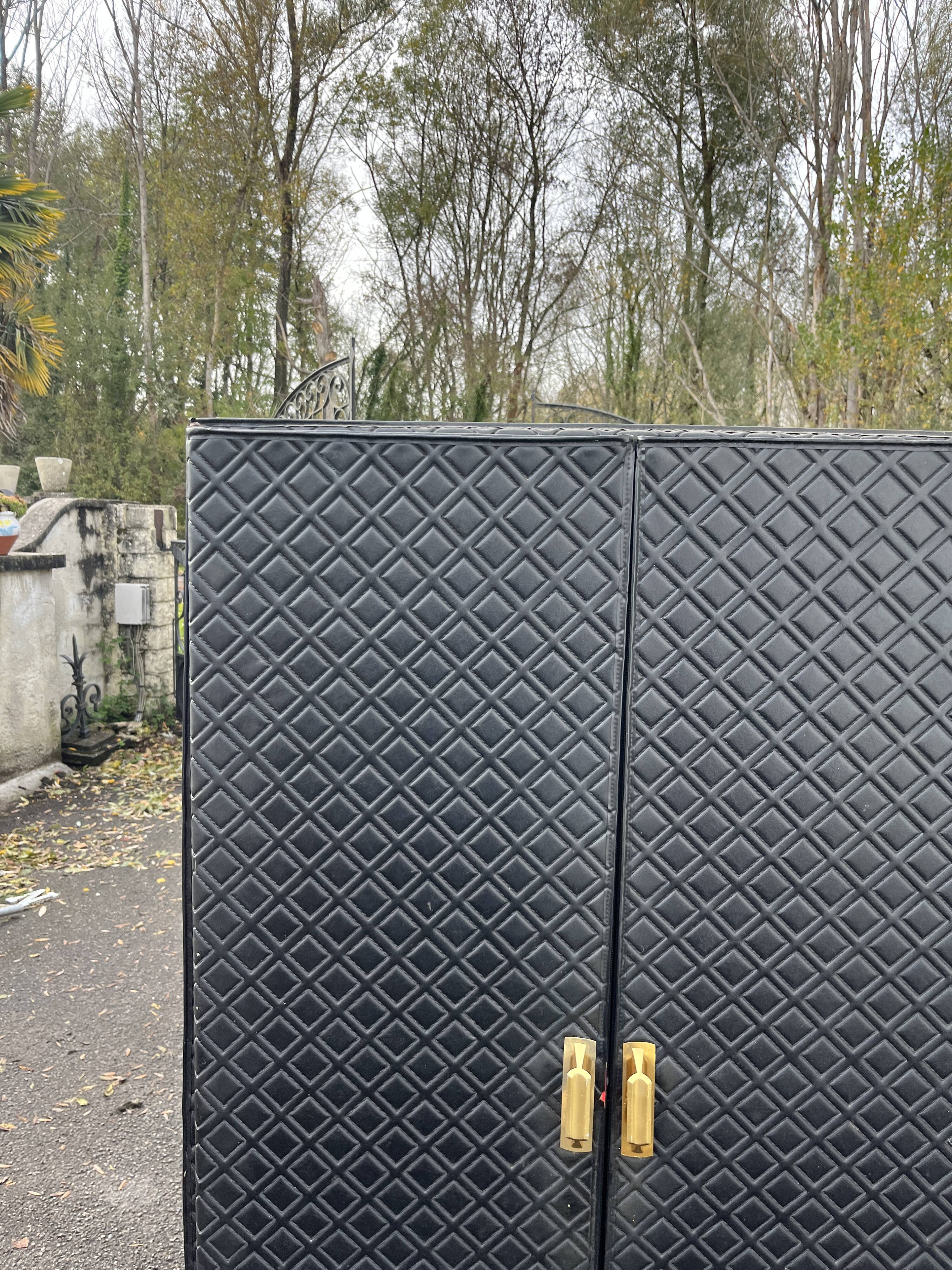 Contemporary wardrobe in black faux leather with diamond pattern and gold handles.