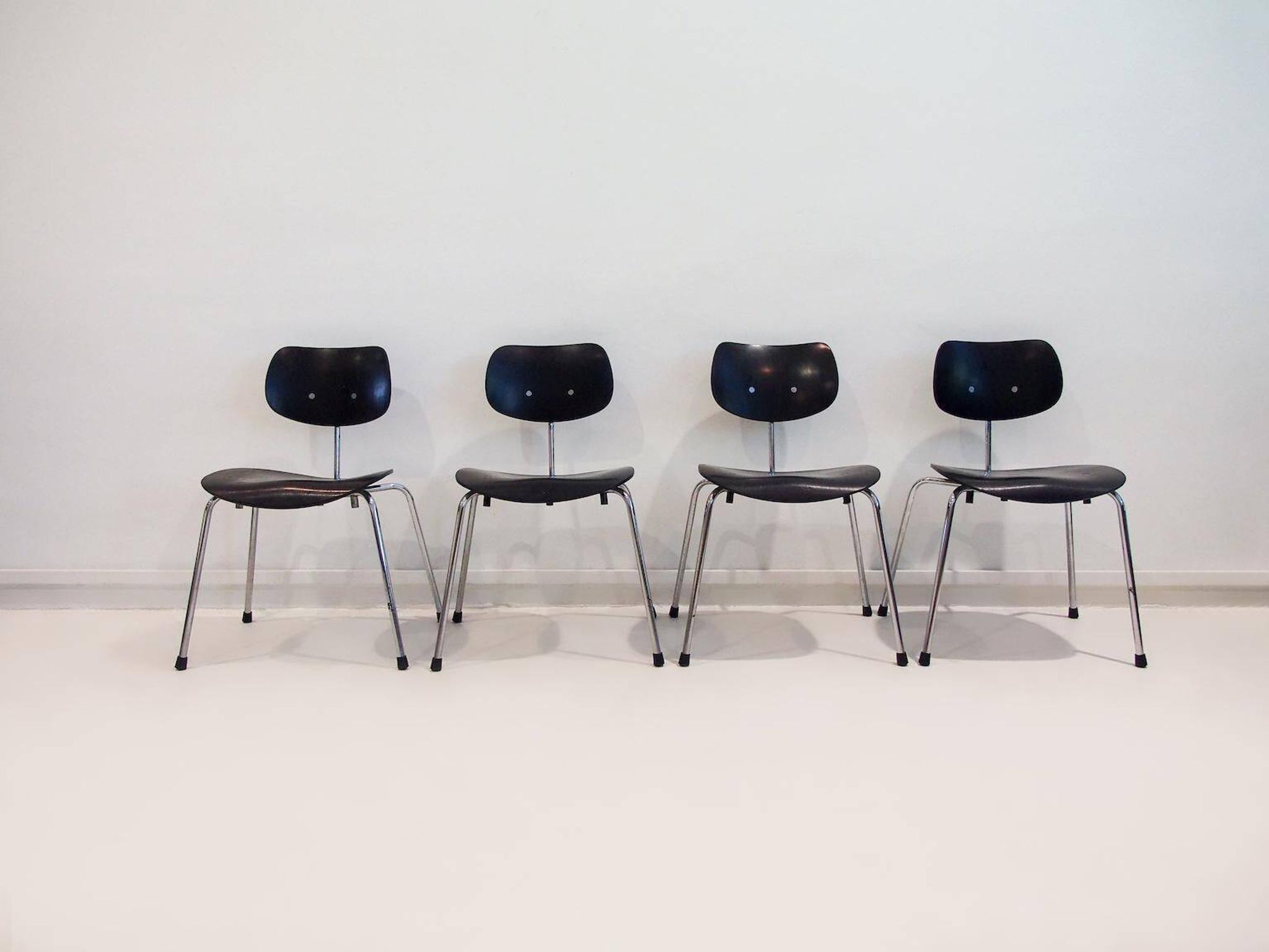 Set of four Egon Eiermann model SE 68 chairs in black lacquered plywood and steel.