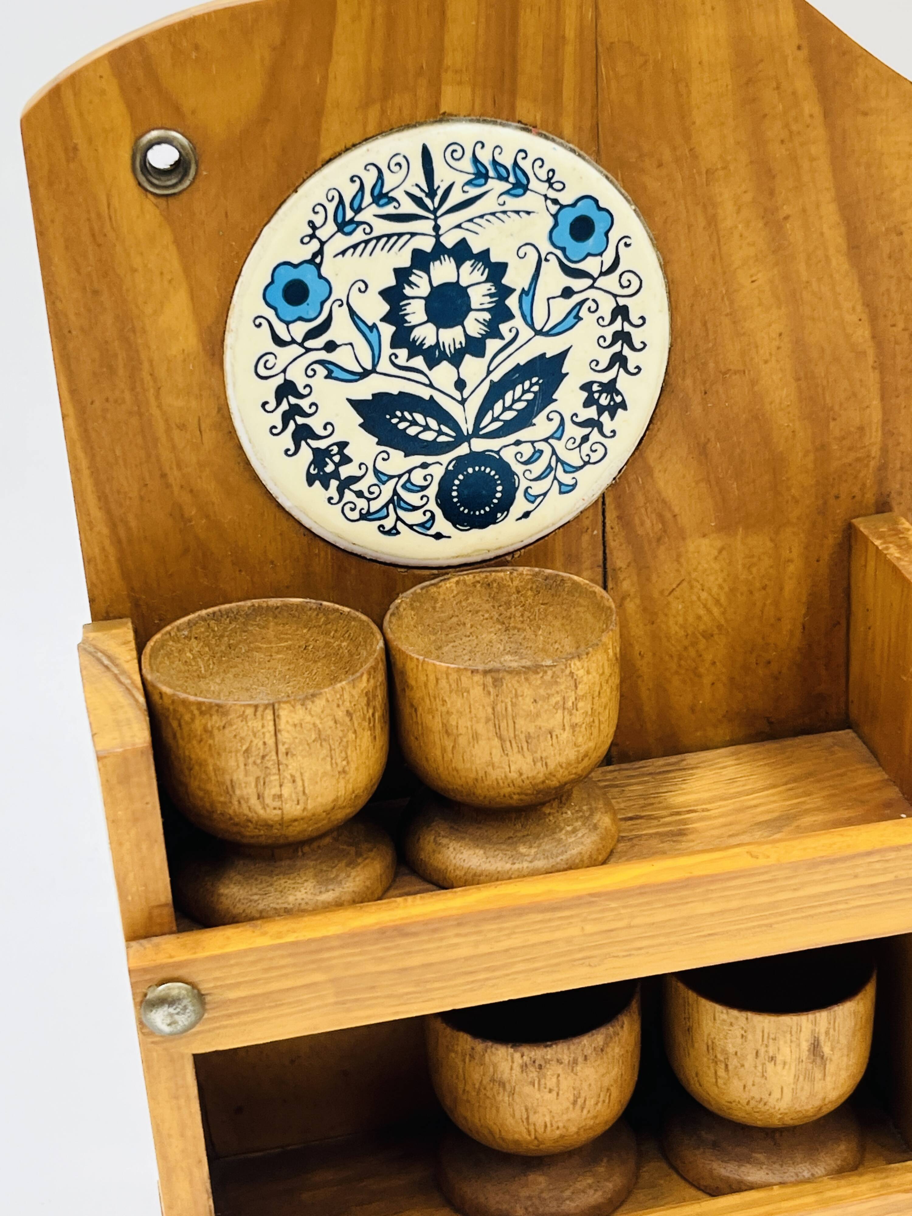 Wall-mounted egg cup holder and wooden utensil holder.