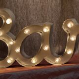 Enseigne lumineuse en lettrage aluminium formant le mot "bar"