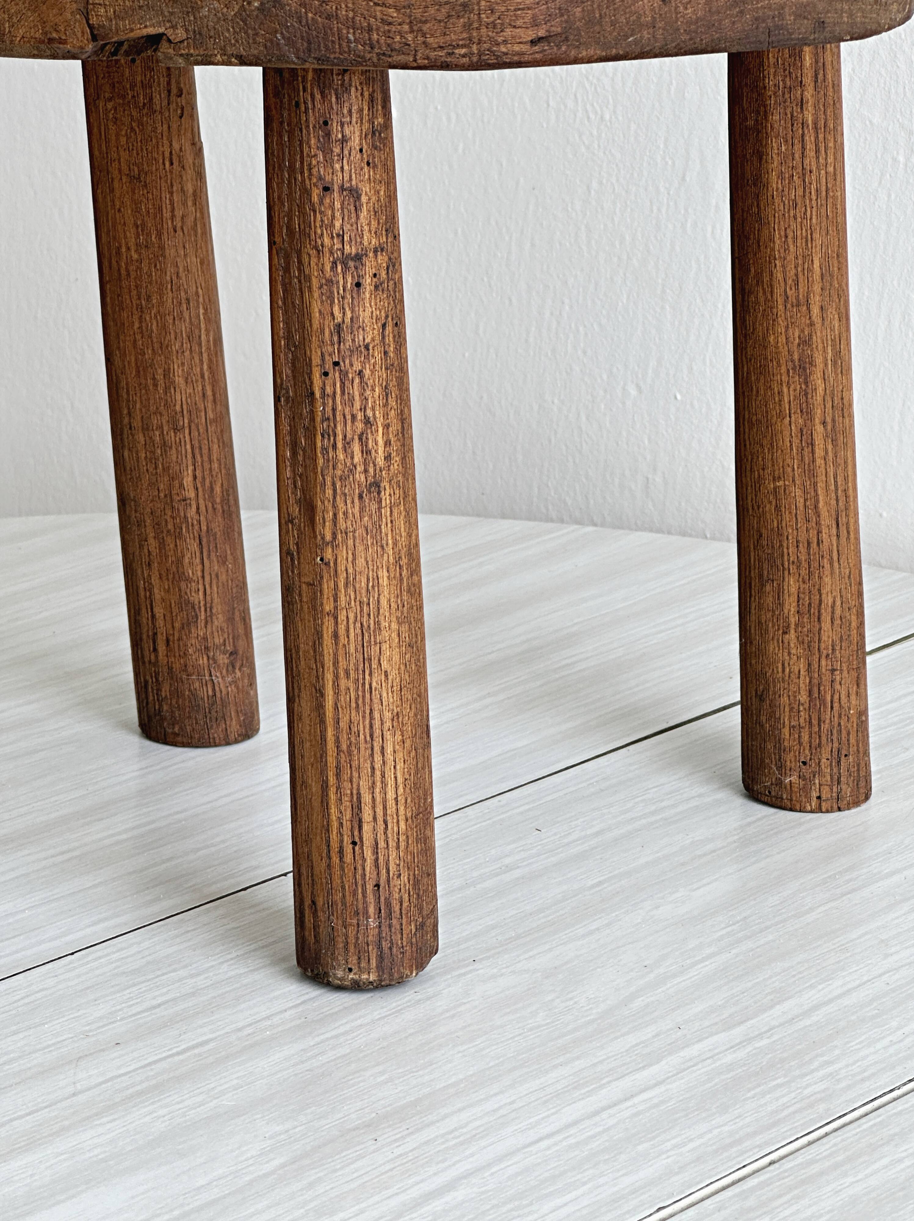 Antique three-legged stool made of raw solid wood.