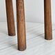 Antique three-legged stool made of raw solid wood.