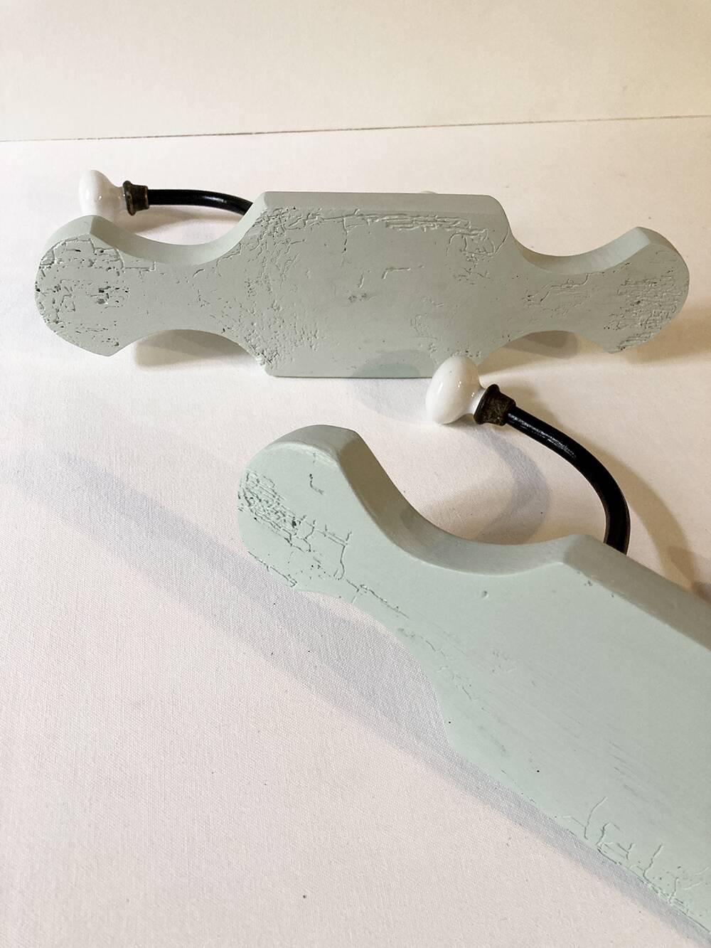 Antique metal and porcelain coat hooks, painted wooden support
