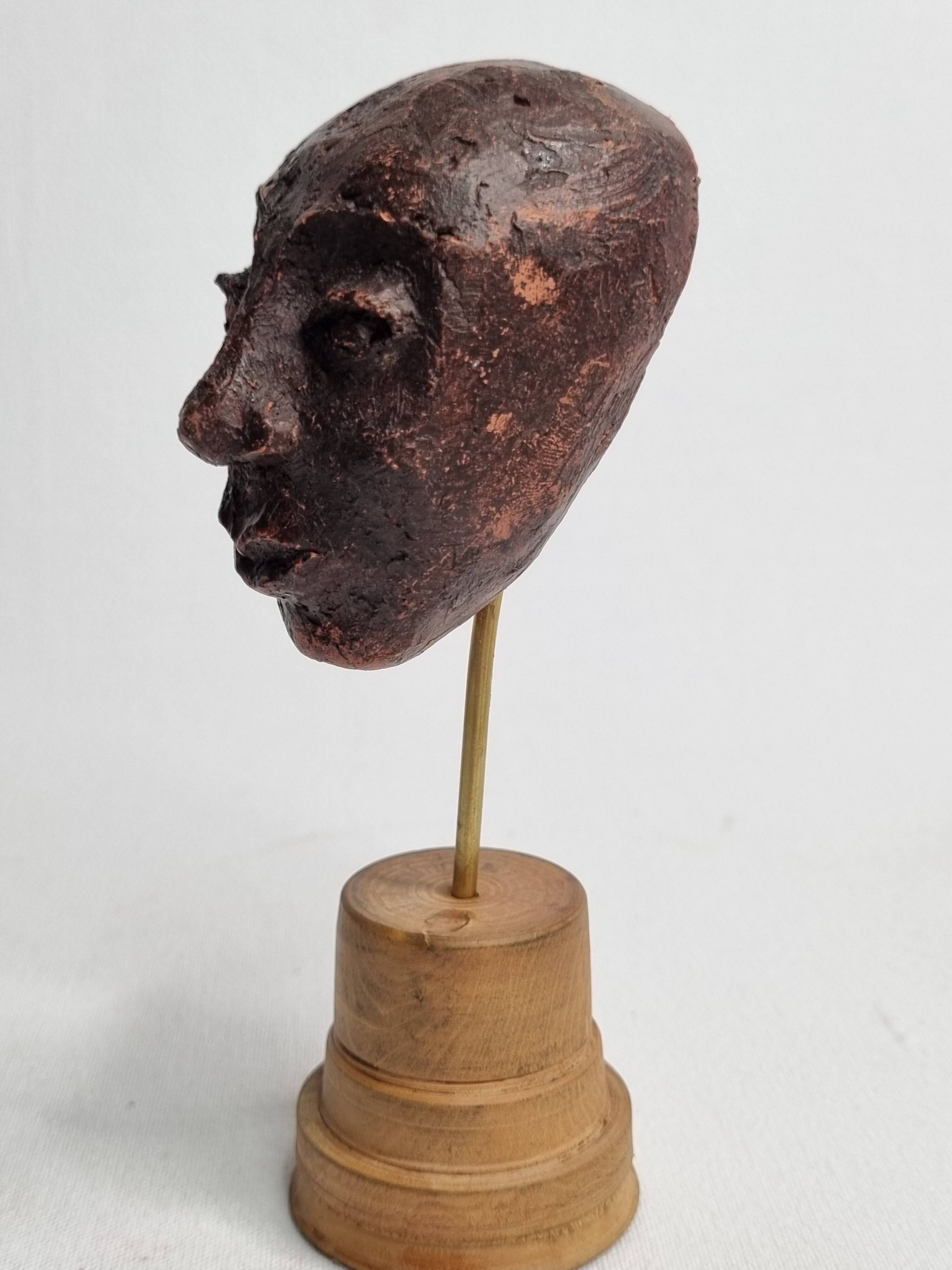 Expressive sculpted head in patinated terracotta on wooden base, 14 cm