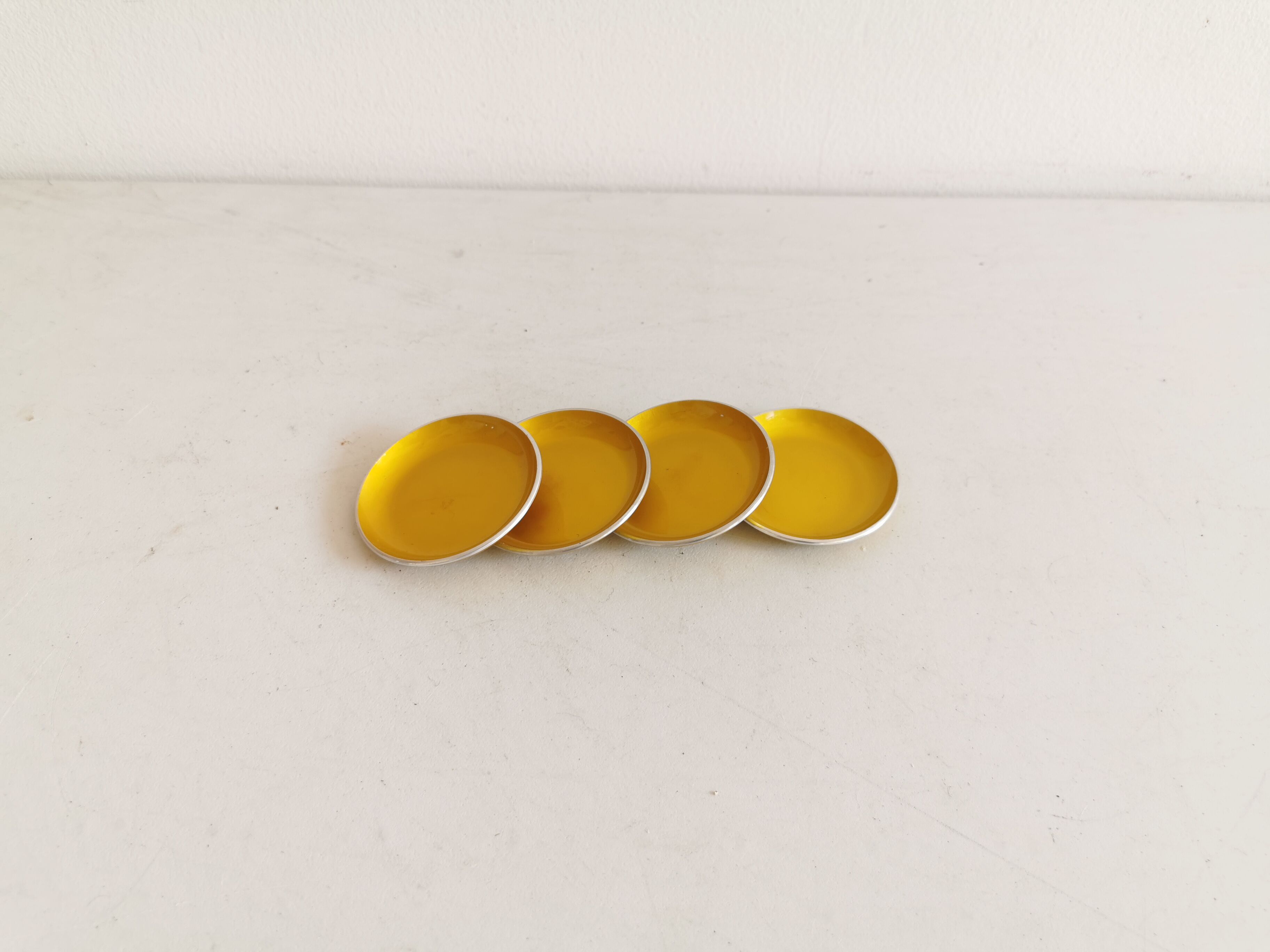 Ensemble de quatre sous-verres émaillés - cendriers de couleur jaune d’origine.
