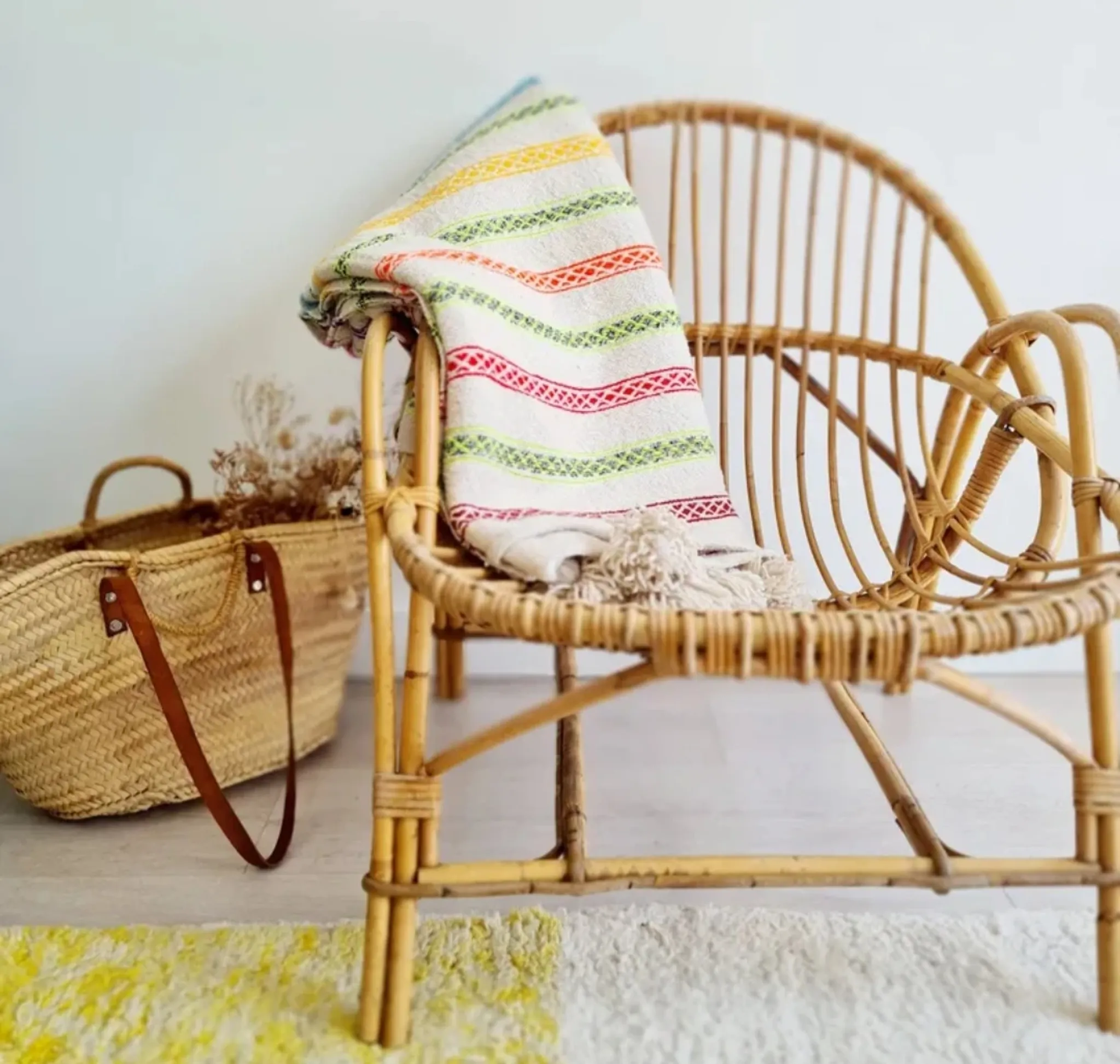Moroccan plaid made of handwoven wool, decorated with stripes and pom poms.