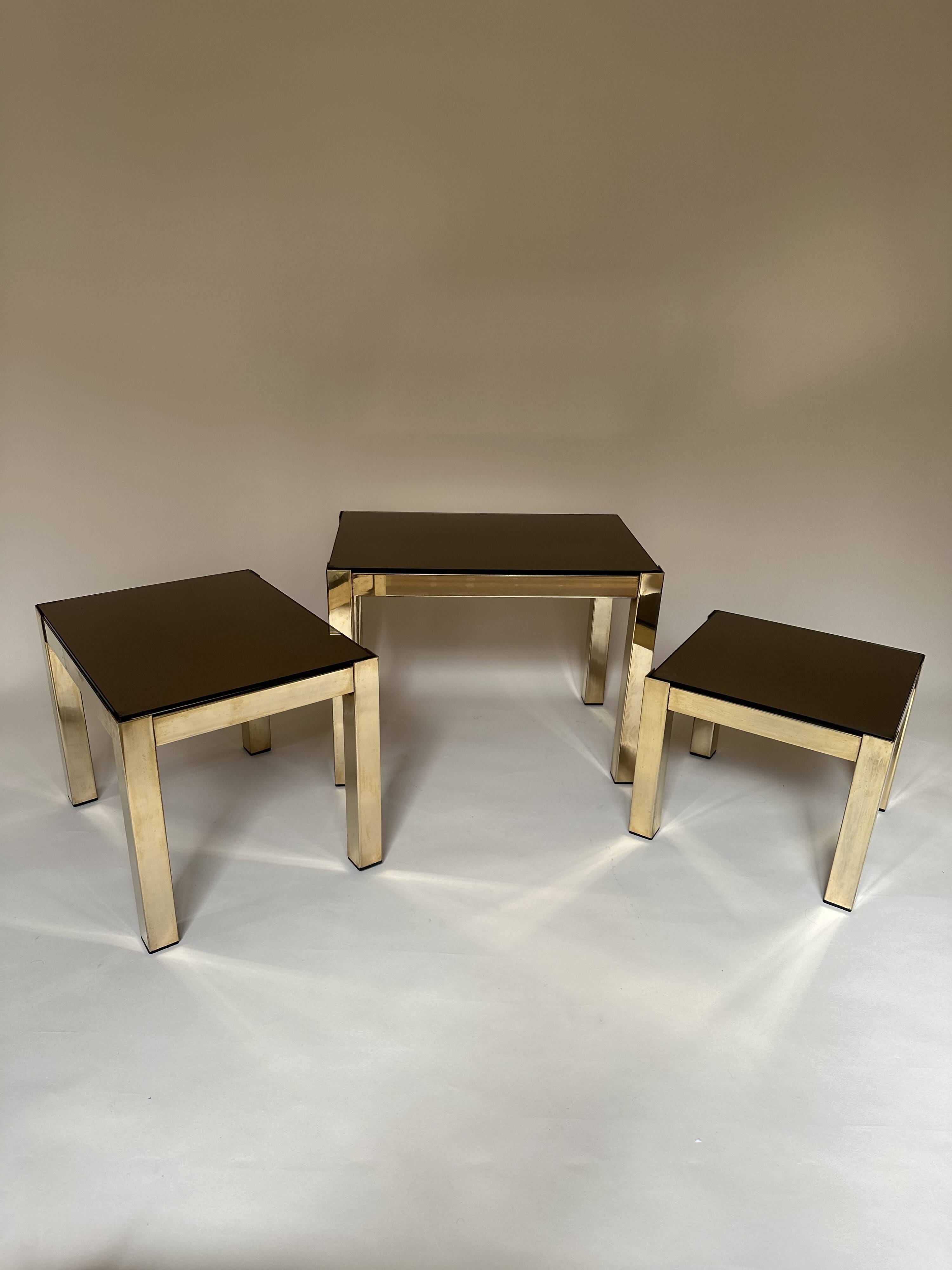 Set of three nesting side tables in brass and smoked mirror.