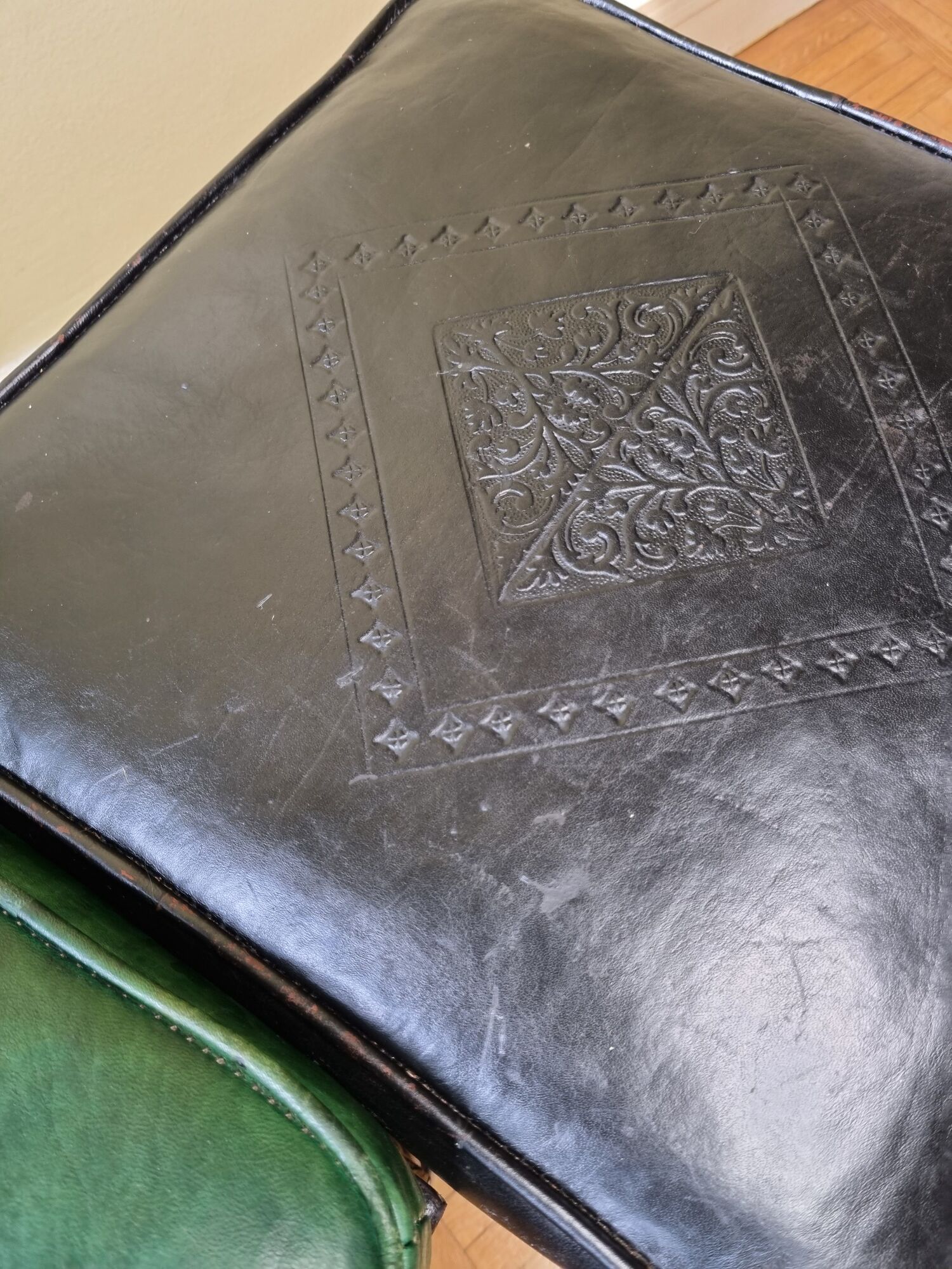 Pair of Moroccan poufs in stamped leather with a carved wooden base, Rabat
