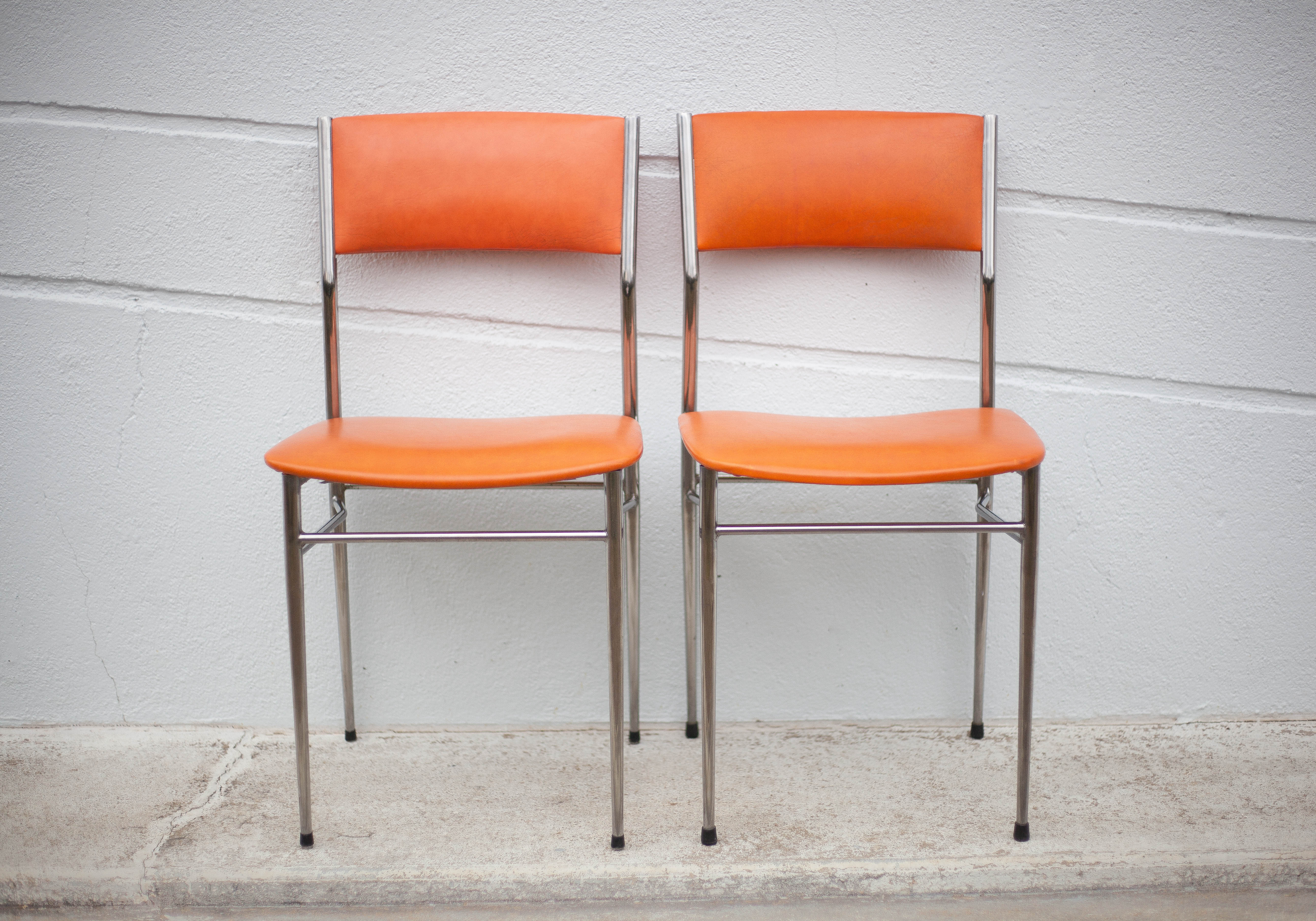 Pair of chrome metal chair and orange skai