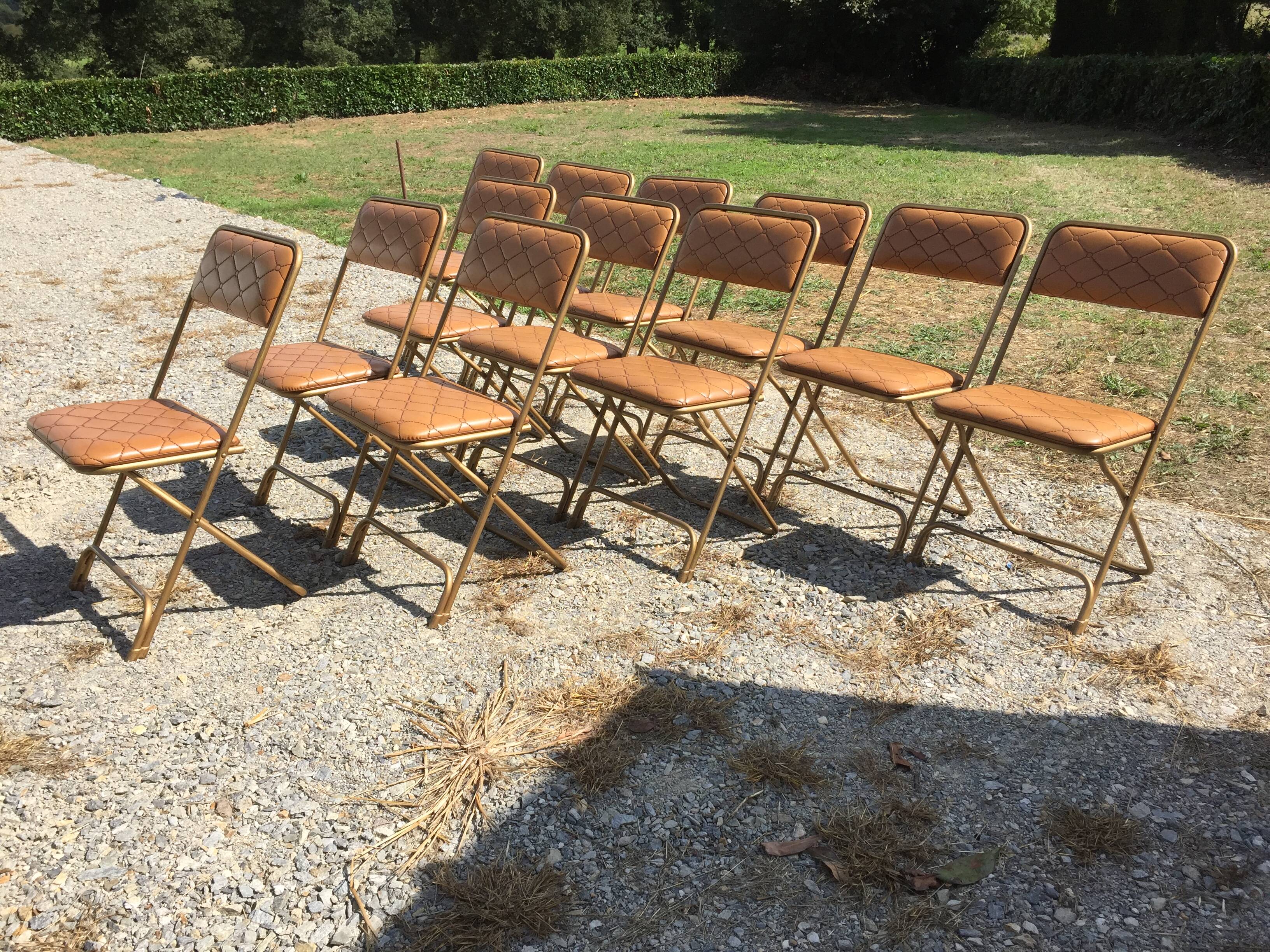 Set de 12 chaises vintage pliantes en skaï assises et dossiers matelassés à piètement tubulaire doré