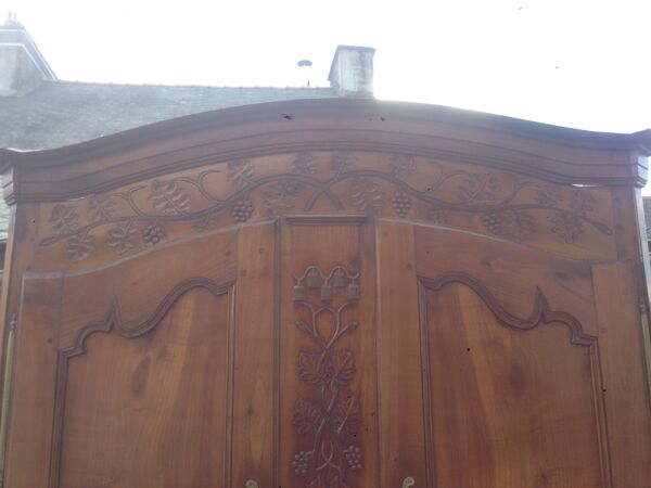 Armoire Louis XV Nantaise sculptée à grappes de raisin, chapeau de gendarme en cerisier fin 19eme.
