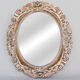 Distressed and carved golden oval mirror in wood.