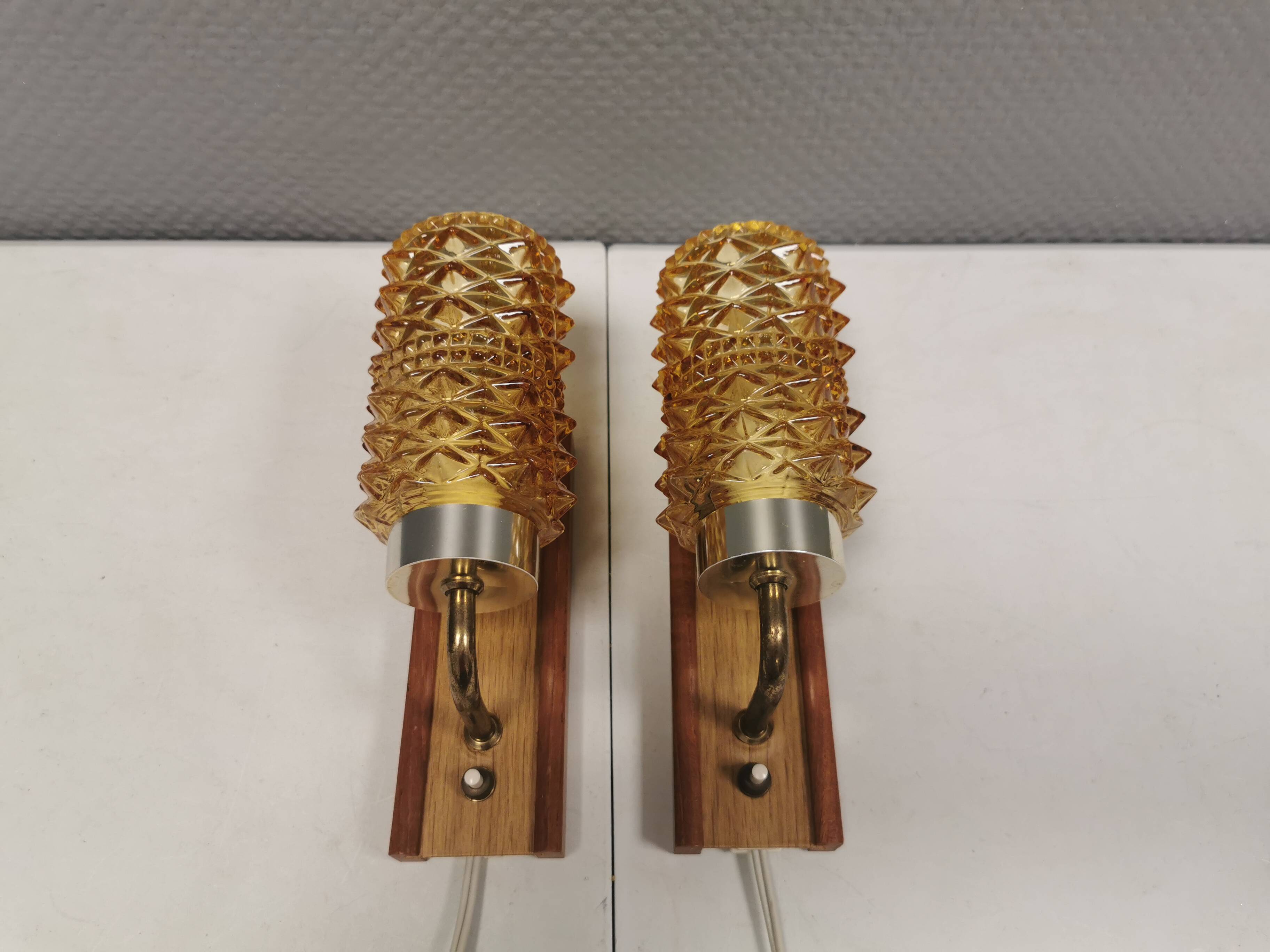 A set of wall lamps in teak wood, with amber colored glass