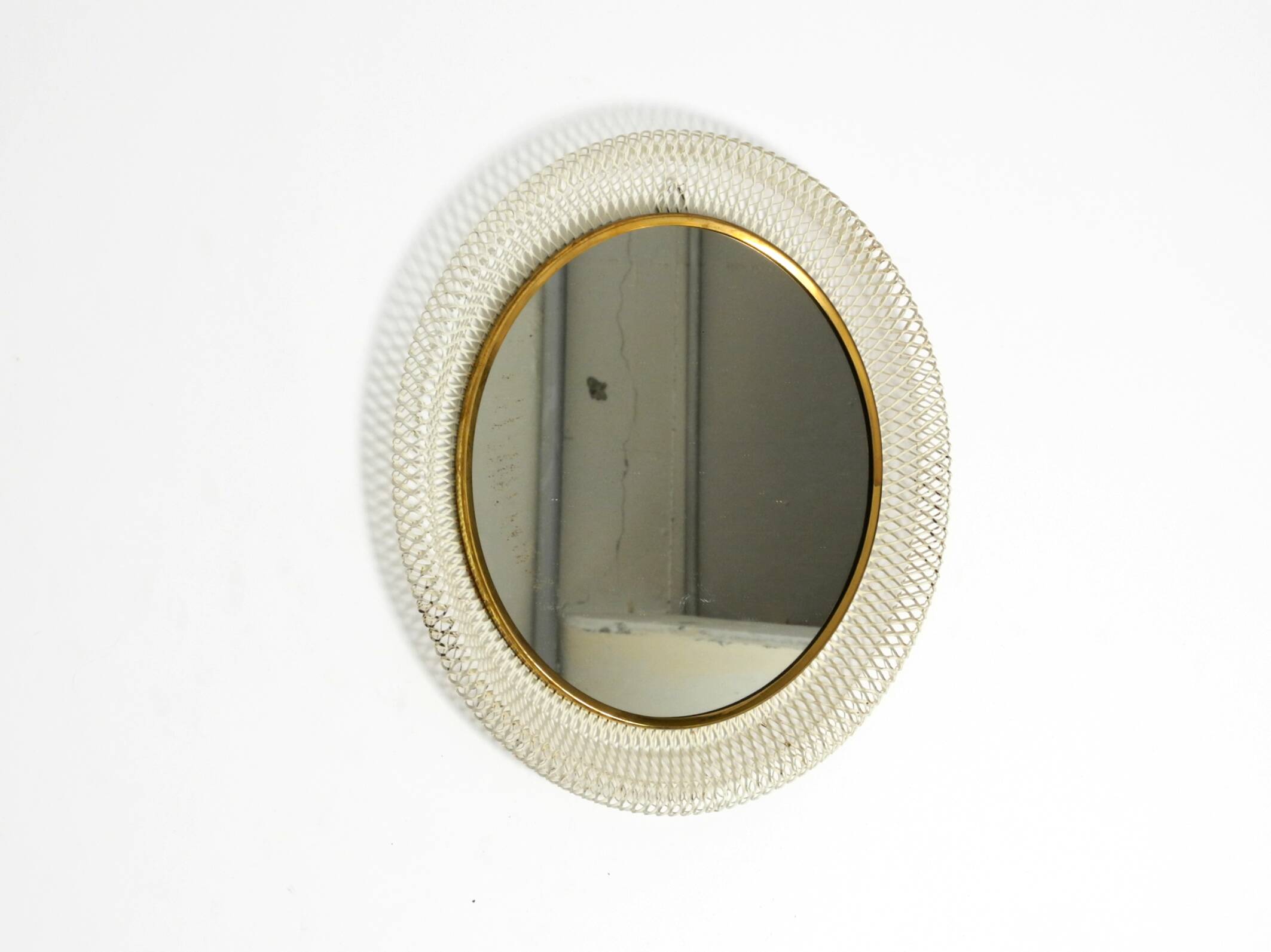 Mid Century Modern round wall mirror with a white expanded metal frame