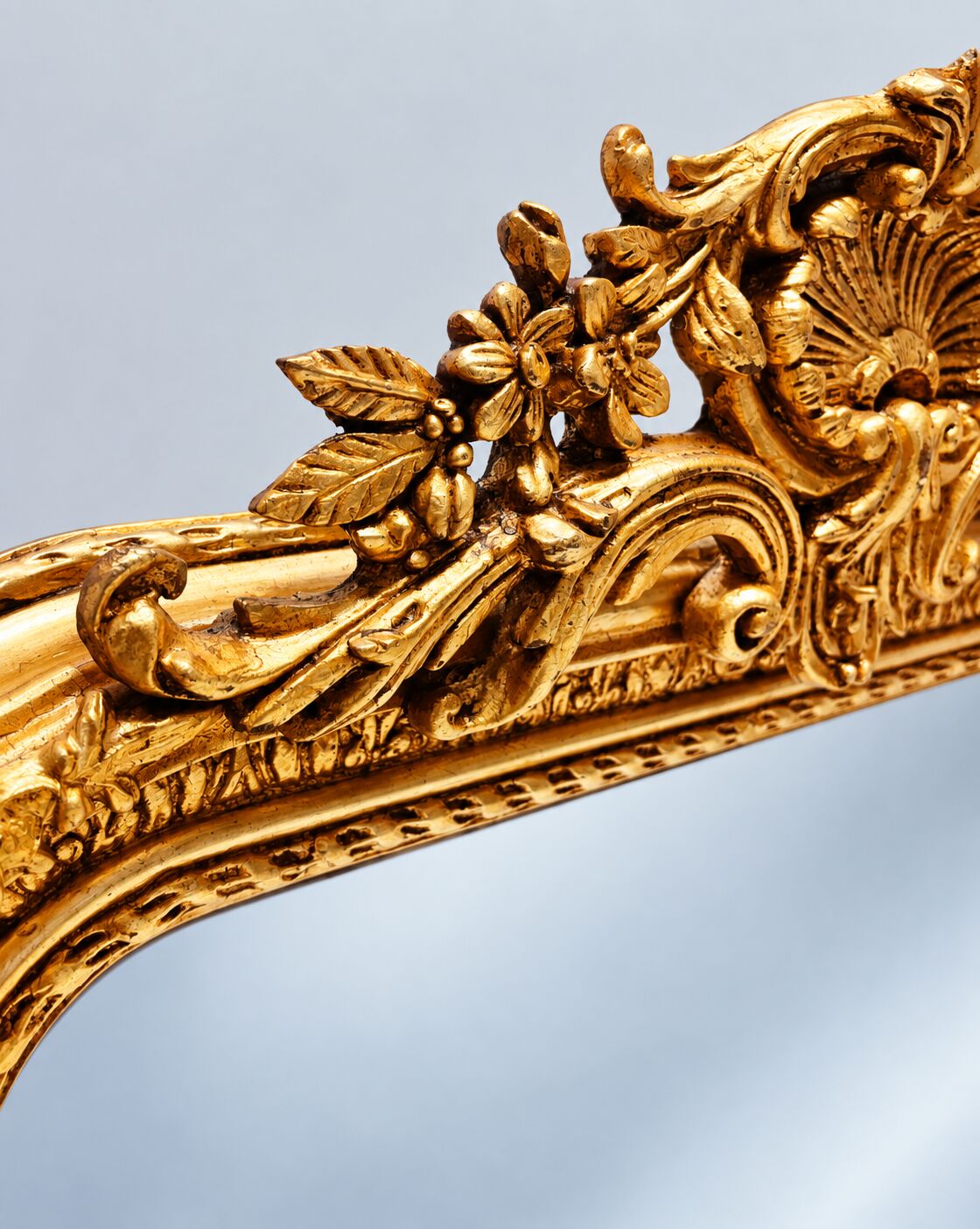 Grand miroir baroque en or avec un crête orné.