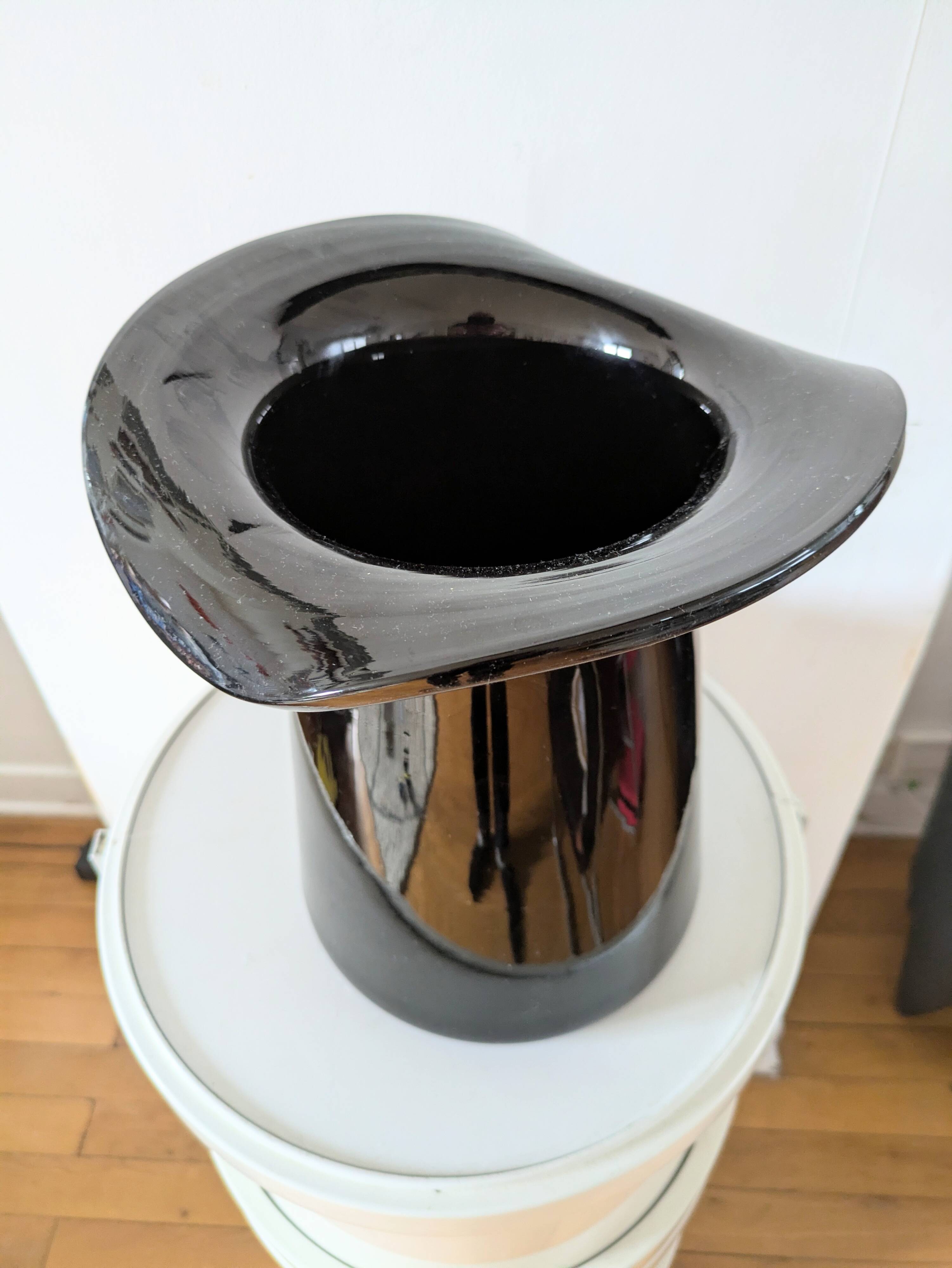Large black glass vase topped with a 70s hat