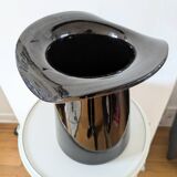 Large black glass vase topped with a 70s hat