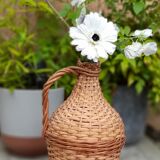 Old demijohn with handle covered with wicker