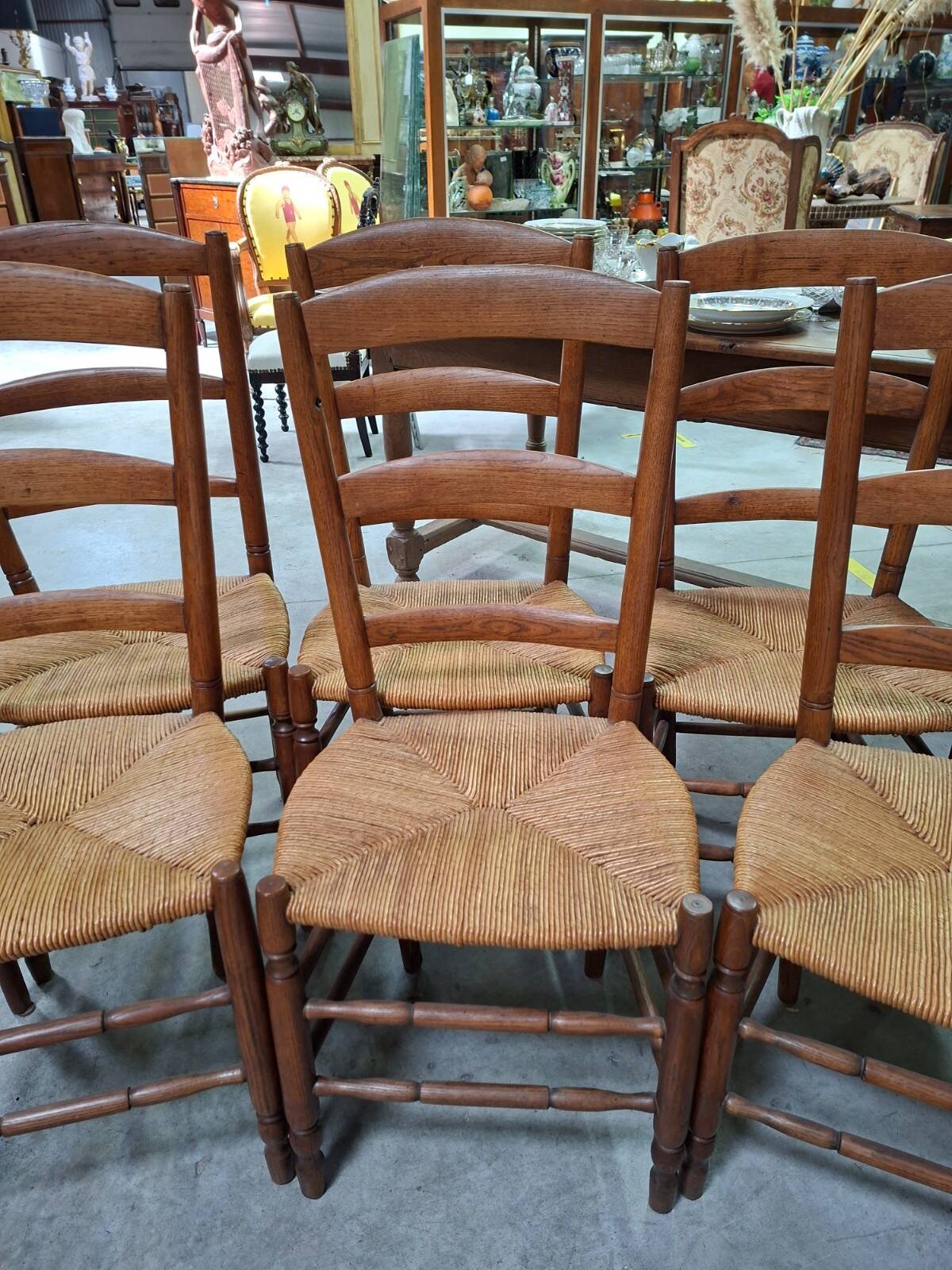 Set of six rustic chairs in natural wood with straw seats.