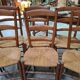Set of six rustic chairs in natural wood with straw seats.