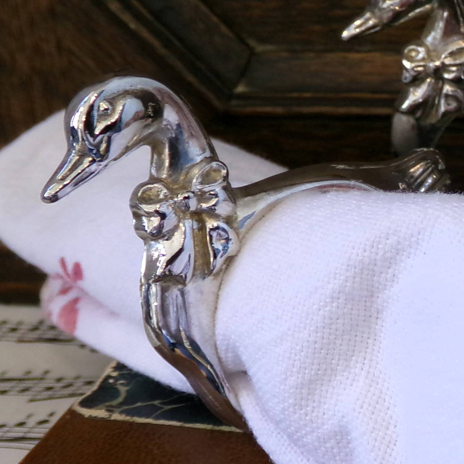 Four silver-plated napkin rings in the shape of a duck/goose