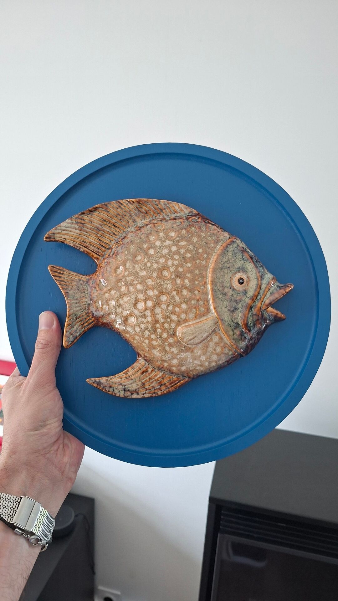 Vallauris ceramic wall sculpture of a relief fish on a blue plaque.