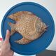 Vallauris ceramic wall sculpture of a relief fish on a blue plaque.