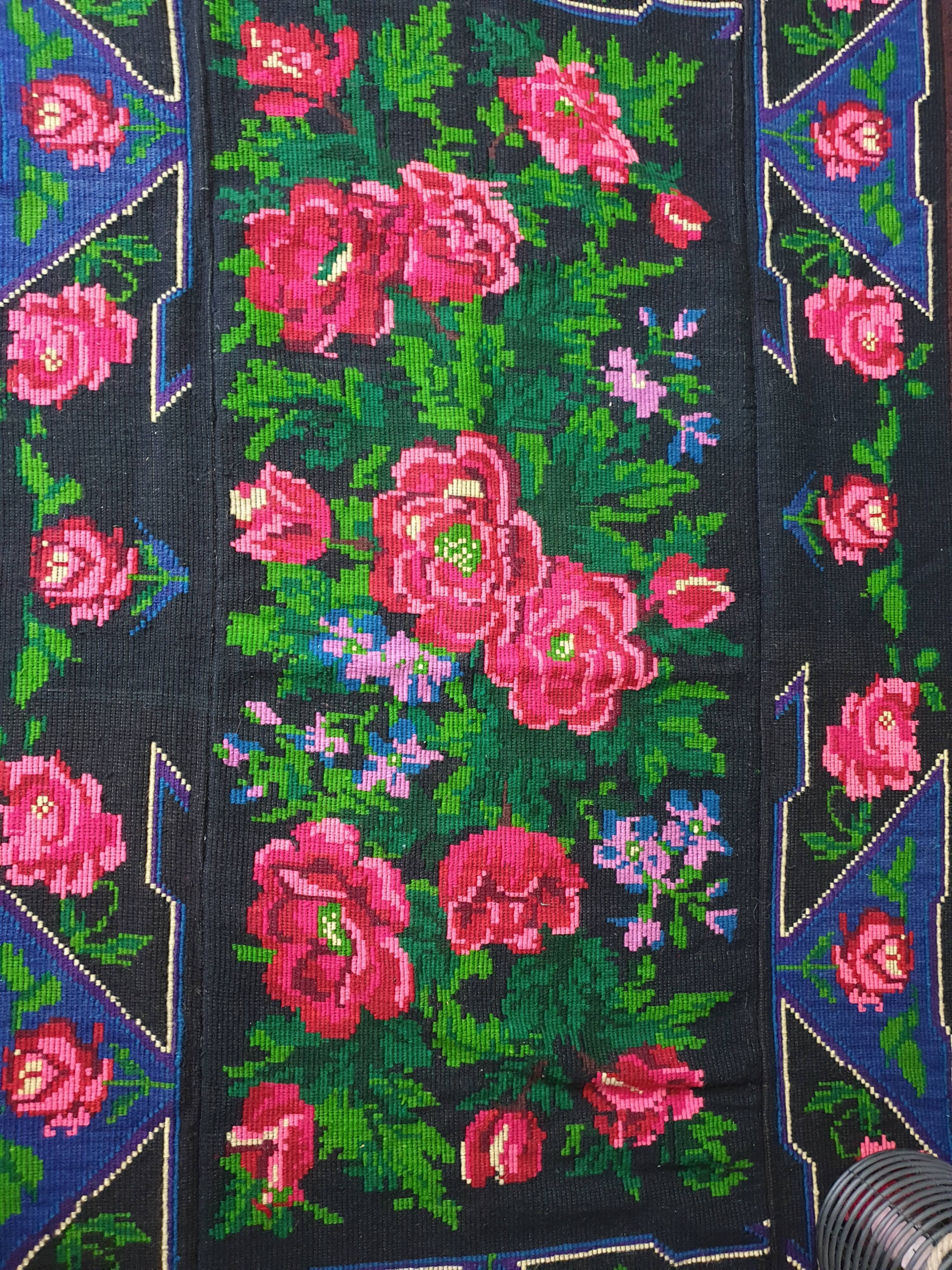 Handwoven floral wool rug, black background with pink roses