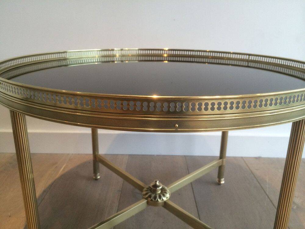 Round coffee table in brass with a black lacquered glass top by Maison Jansen.