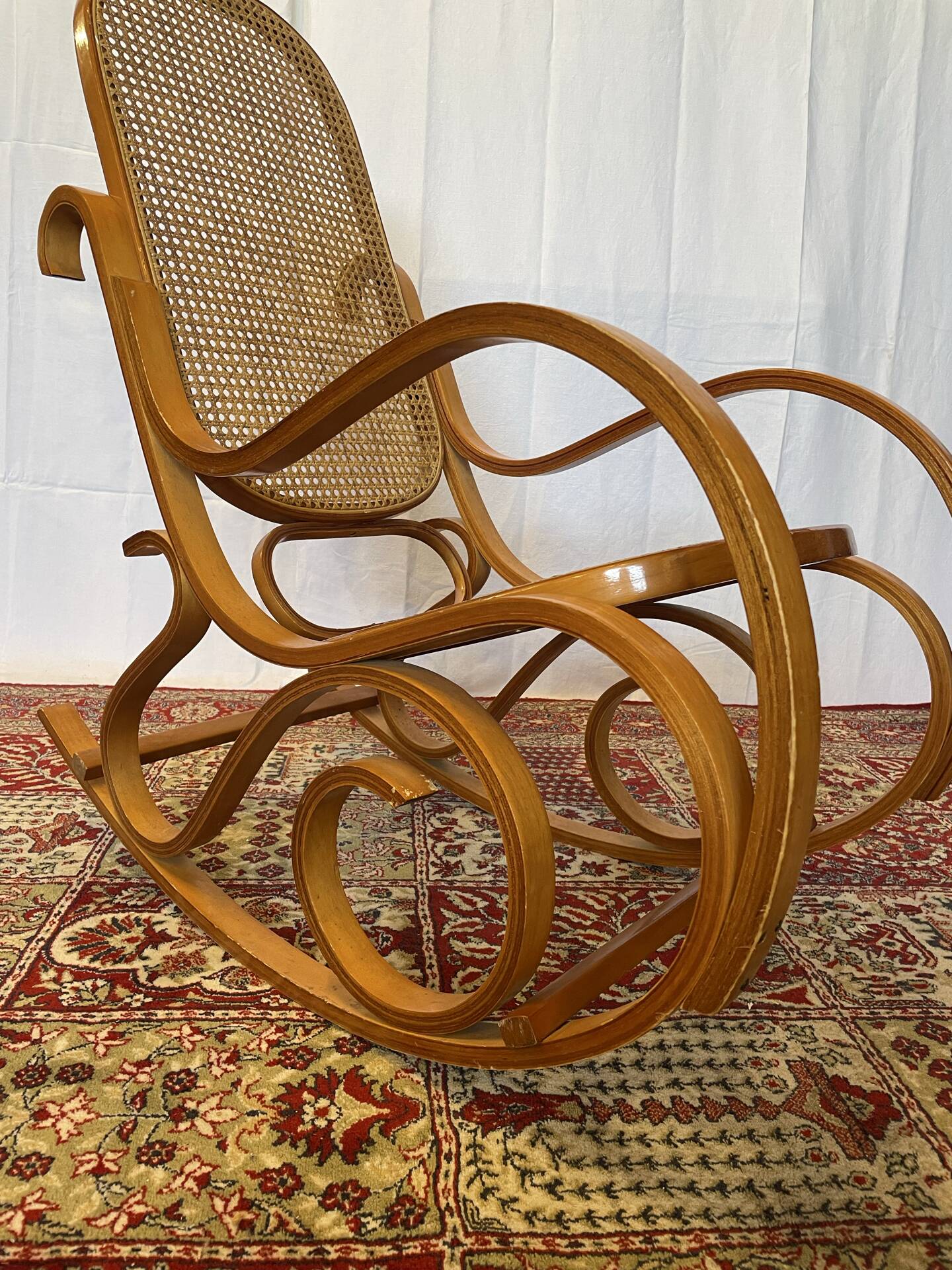 Antique rocking chair in curved wood and caning.