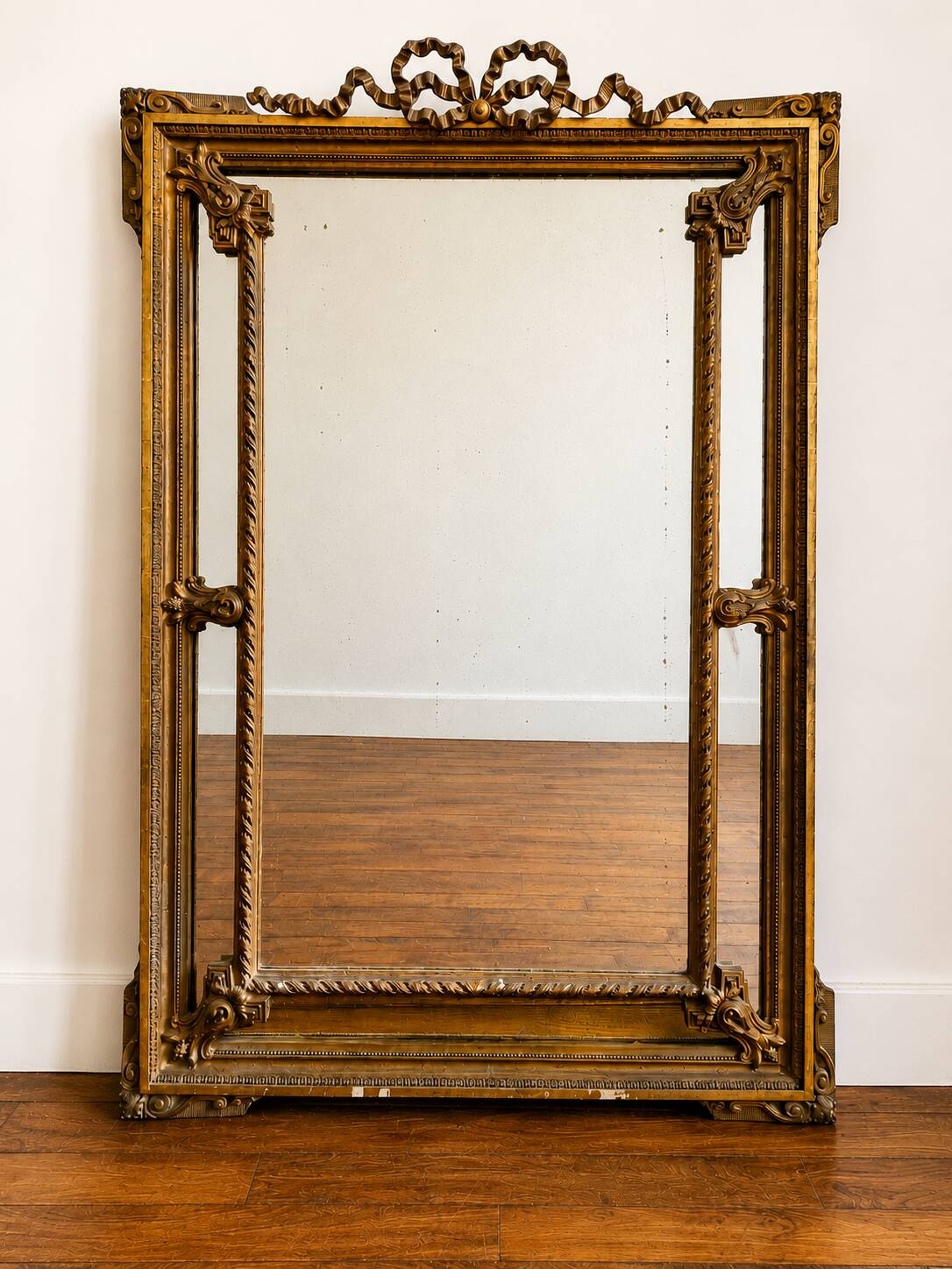 Large Napoleon III mirror 130 × 93 cm — gilded frame sculpted with ribbon pediment.