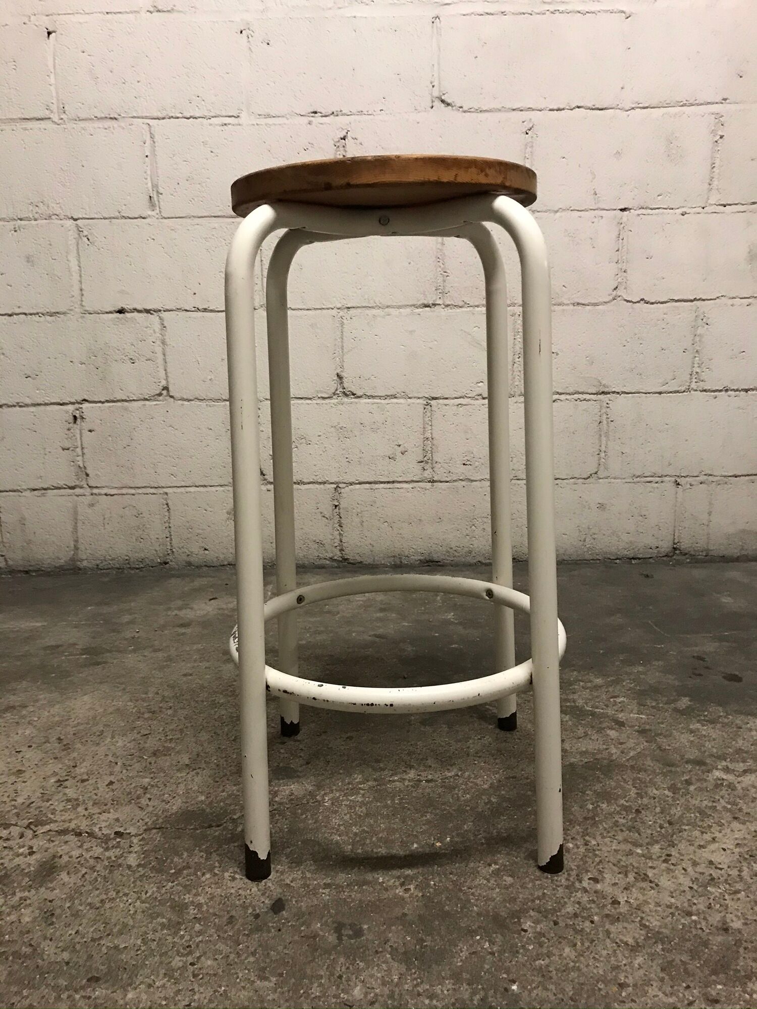 Vintage bar stool in white lace-up, round wooden seat rests circular feet