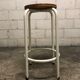 Vintage bar stool in white lace-up, round wooden seat rests circular feet