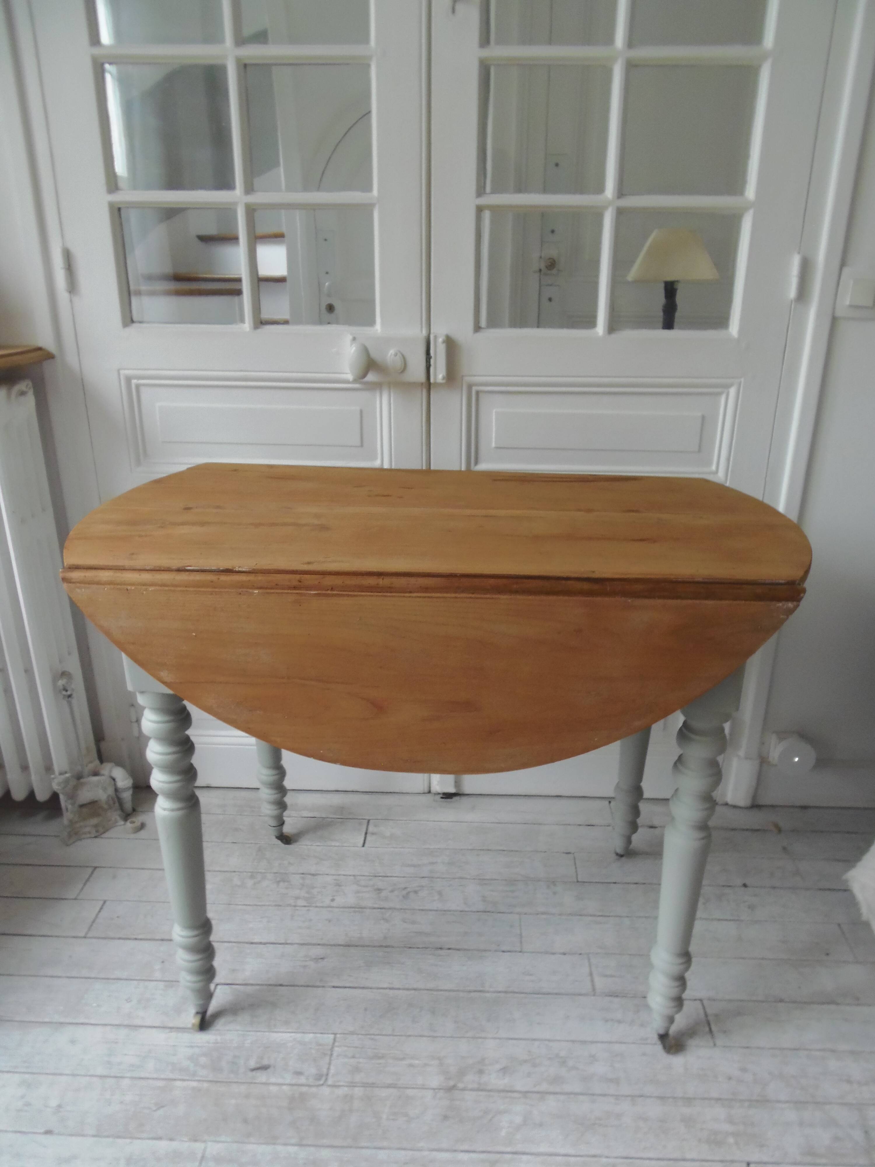 Raised walnut table with drop-leaf top, base on verdigris castors.