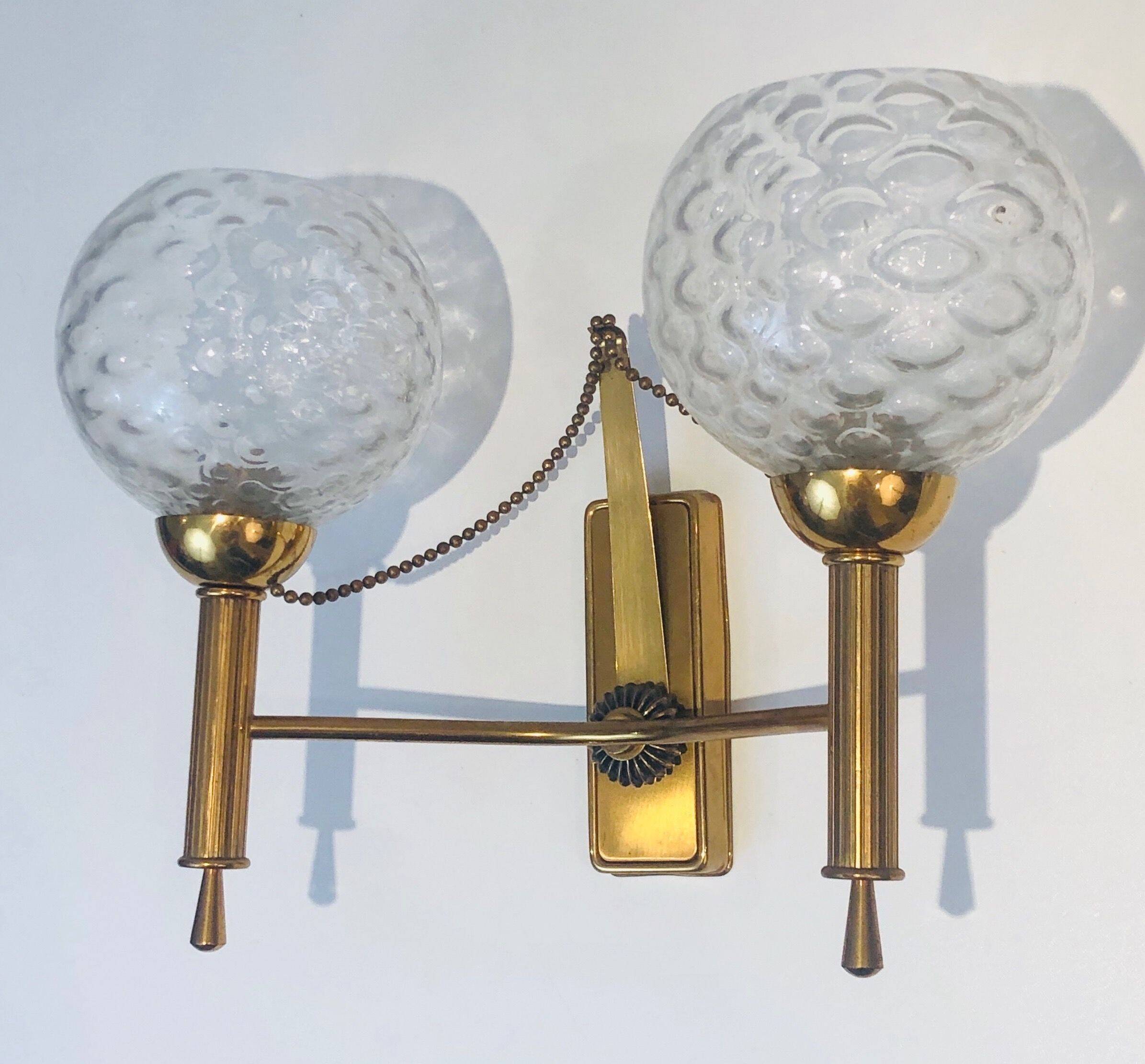 Pair of brass wall lights with glass globes. Around 1970.
