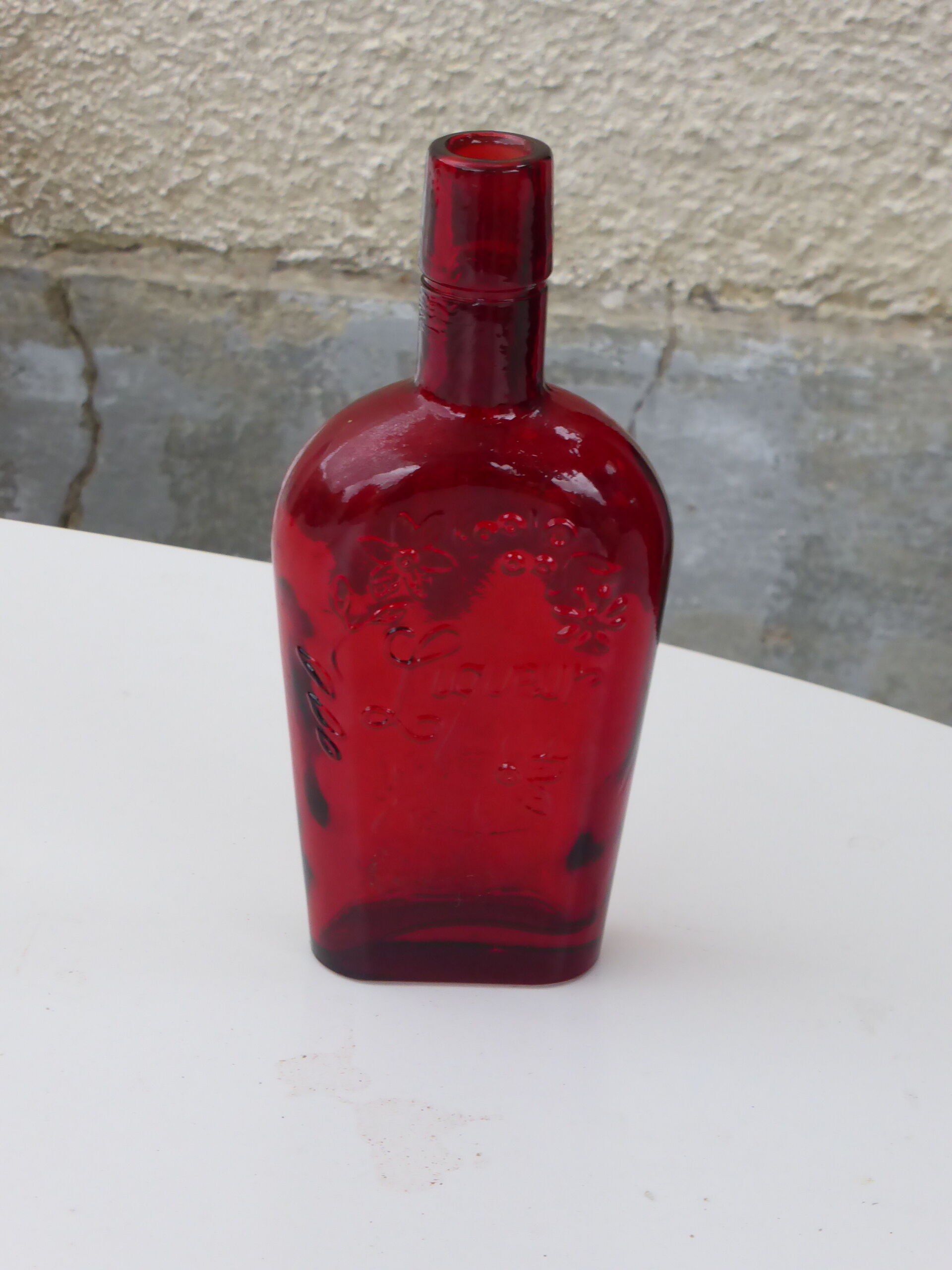 Glass bottle with red glass liqueur, old