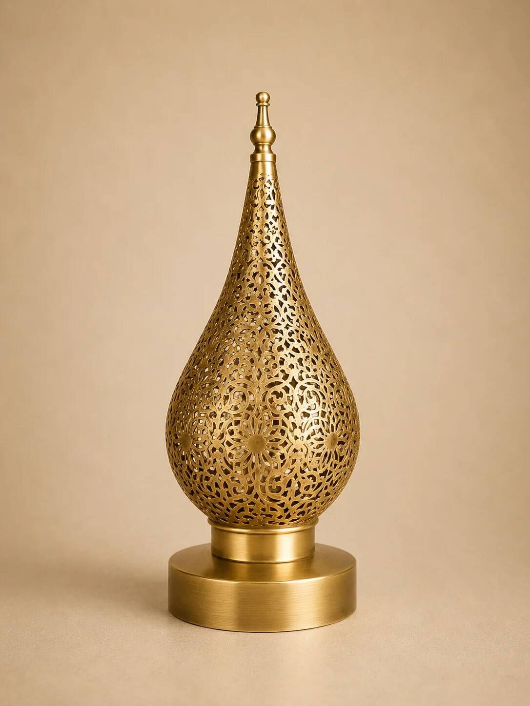 Handmade brass table lamp with a perforated drop-shaped shade.