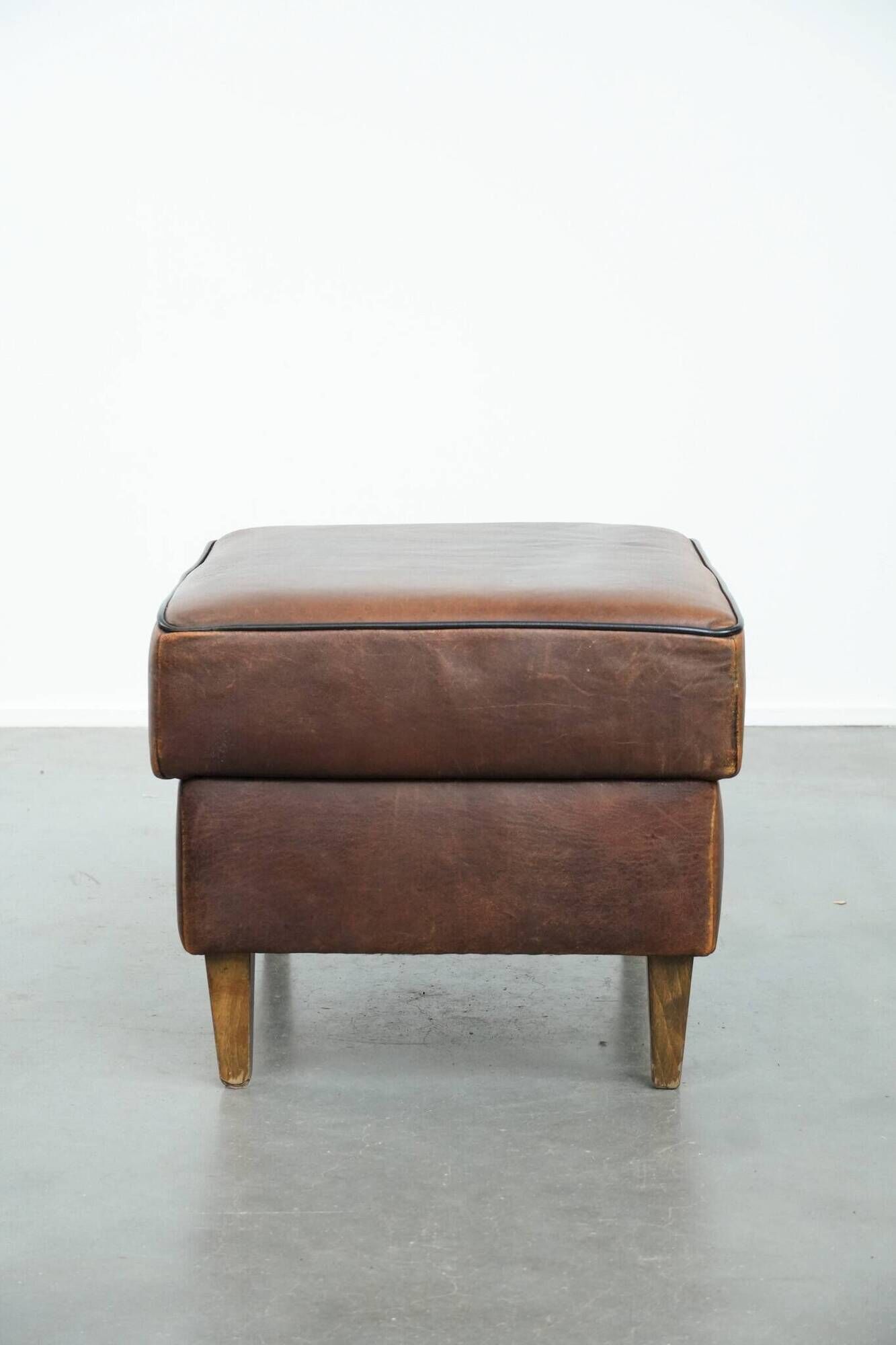 Sturdy vintage sheepskin ottoman in a beautiful large size with black piping