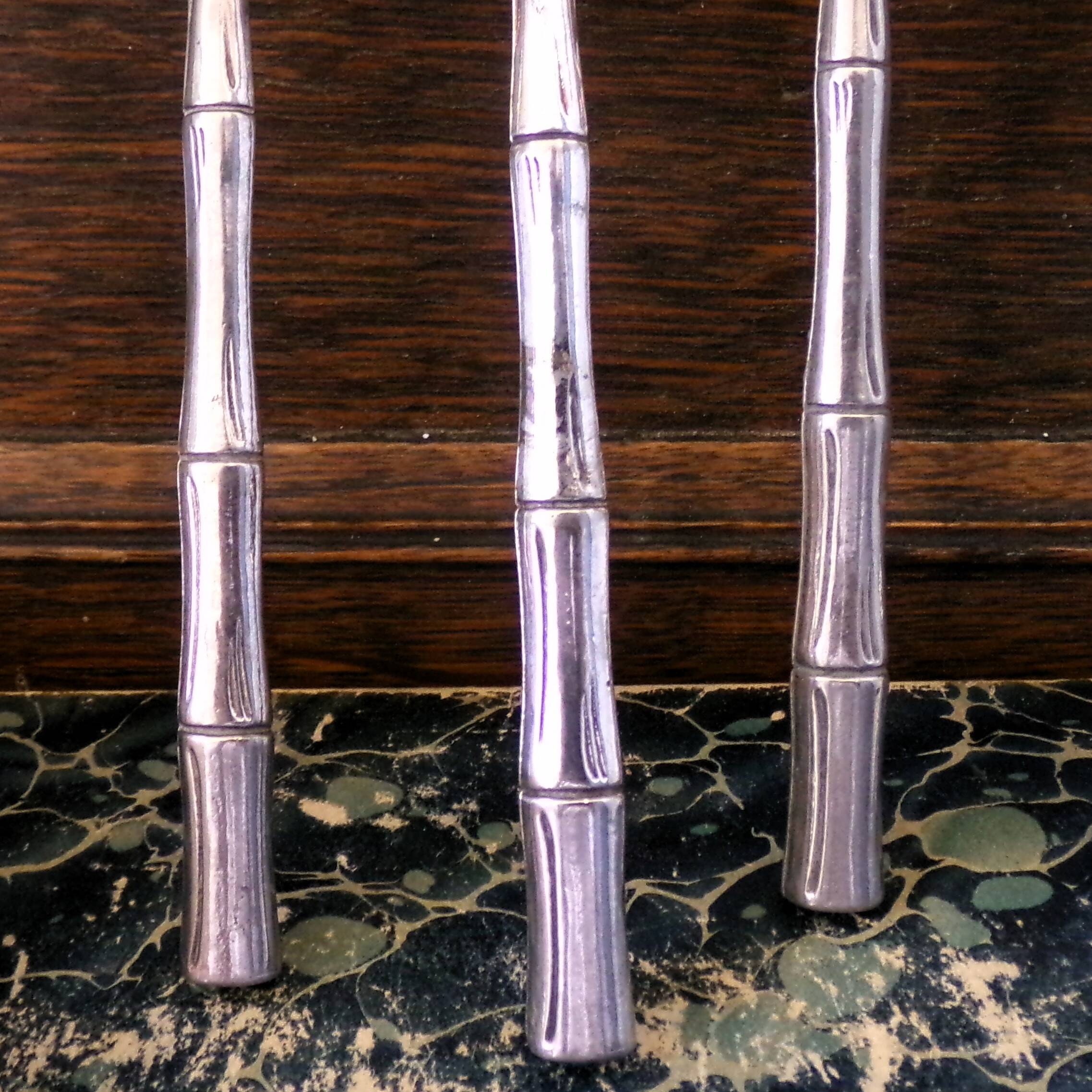 Five silver-plated metal appetizer forks with bamboo-style handles