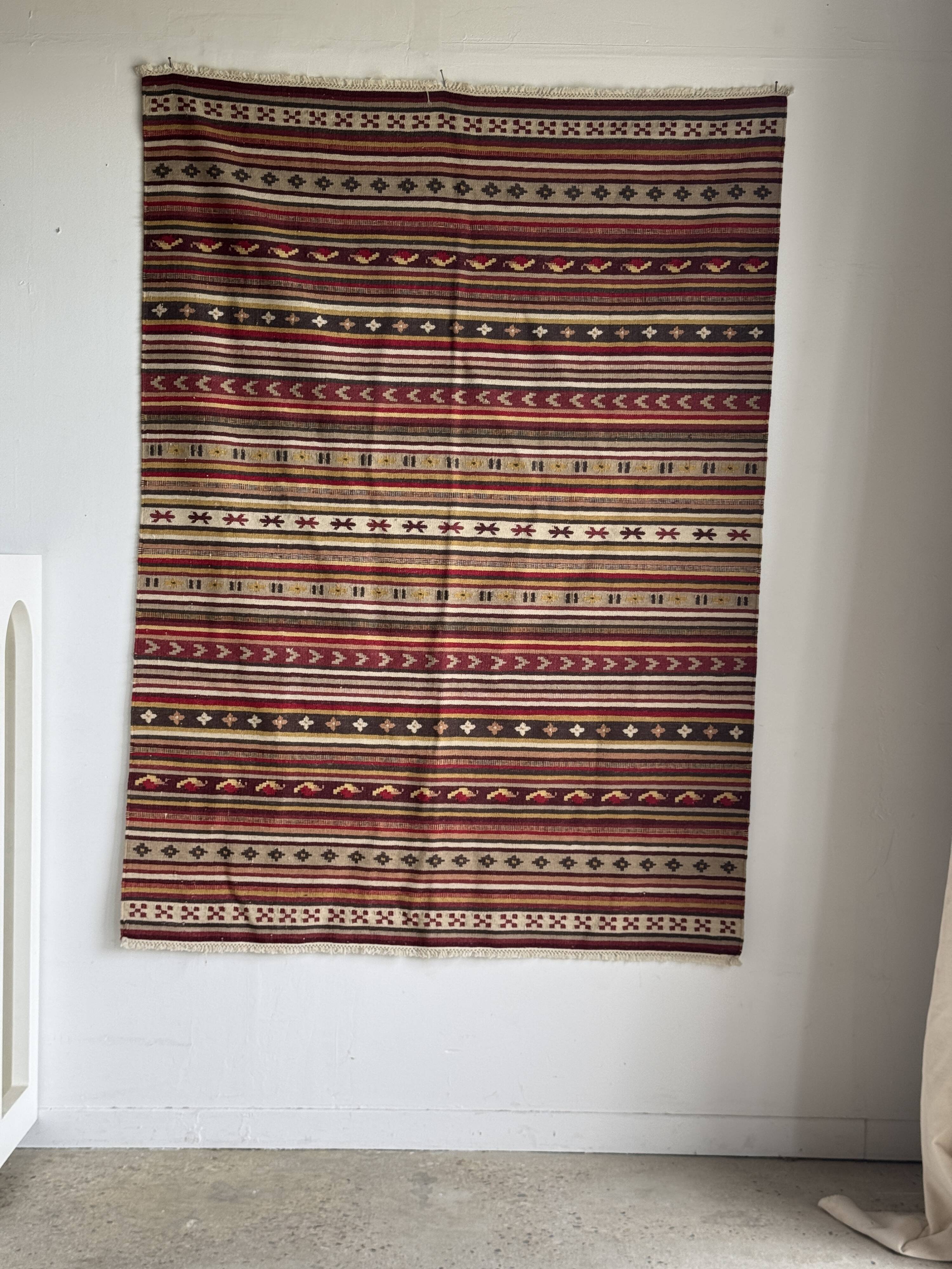 Large Indian rug with red, yellow, and white stripes and geometric fringes.