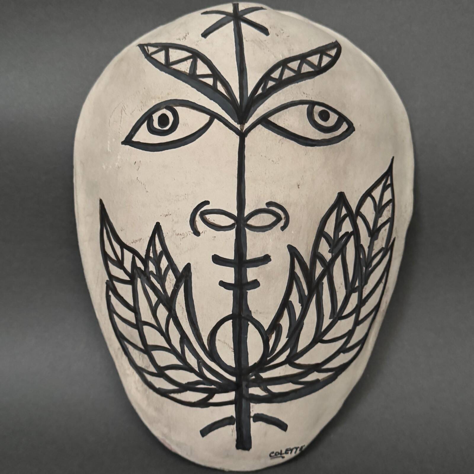 Africanist mask in glazed white terracotta, face signed Colette.