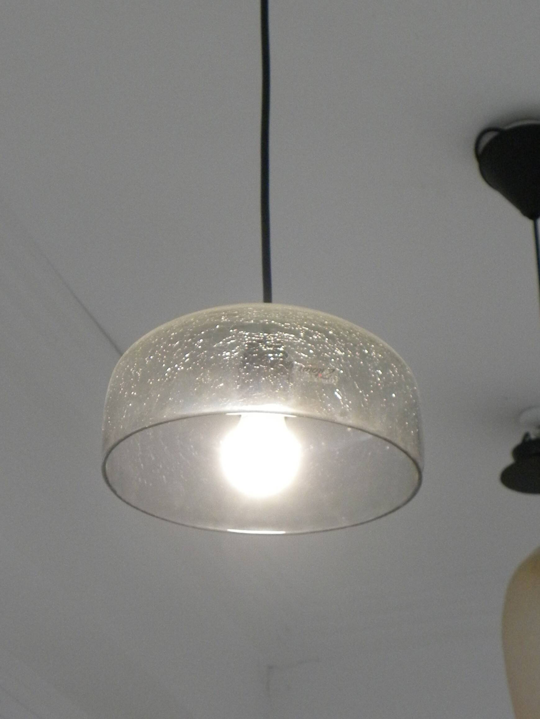 Modern suspended lamp in cracked blown glass, minimalist design.