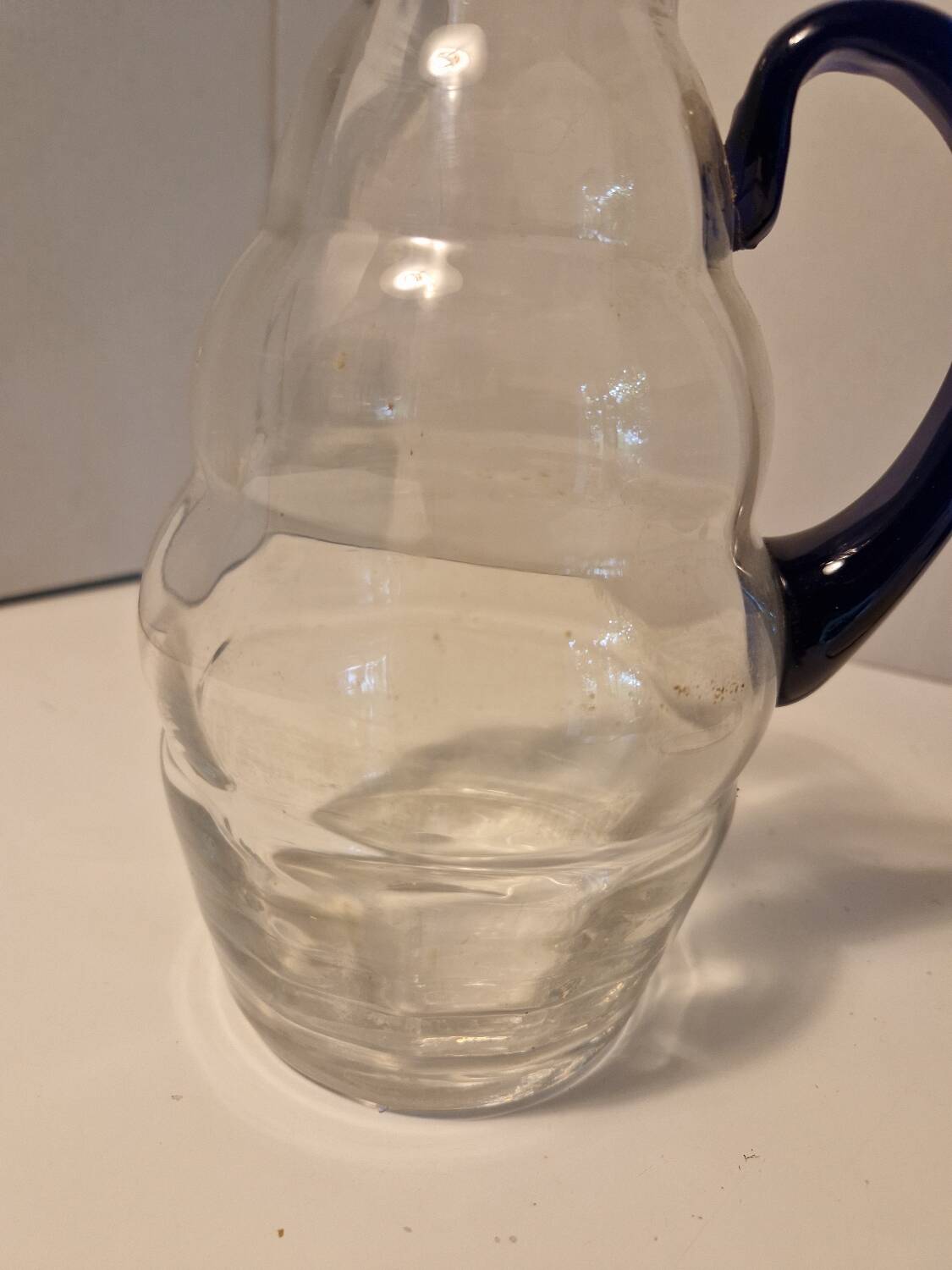 Glass carafe with wavy body and blue handle