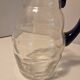 Glass carafe with wavy body and blue handle